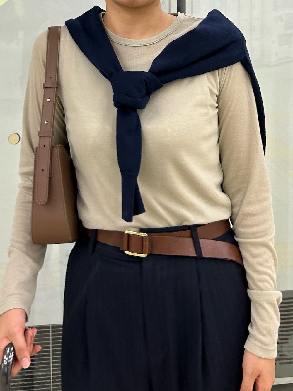 ブルー系のスラックス、ブラウン系のハンドバッグ、ベージュ系のTシャツ/カットソーを着用したレディースの秋コーディネートの5枚目の写真