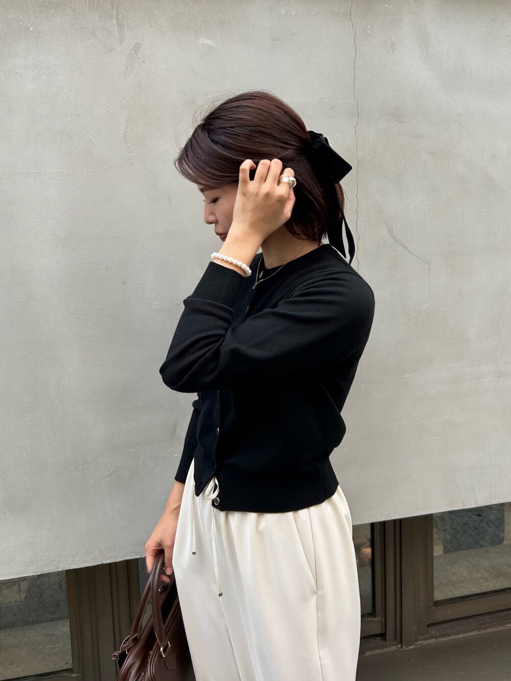 ホワイト系のその他パンツ、ブラウン系のハンドバッグ、ブラック系のニット/セーターを着用したレディースの秋コーディネートの2枚目の写真