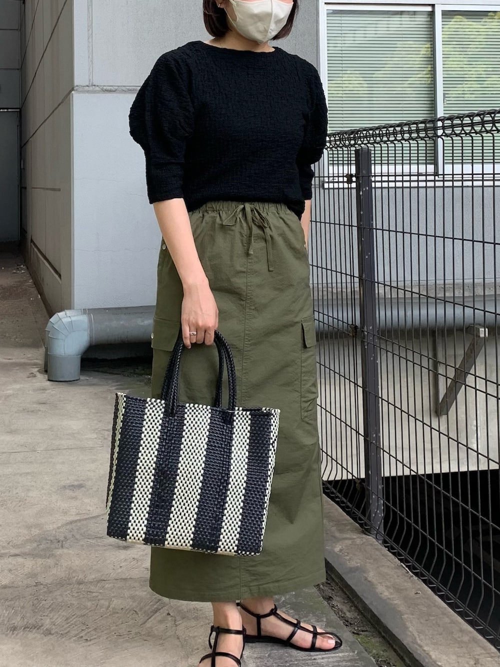 ブラック系のTシャツ/カットソー、グリーン系のスカートを着用したレディースの春コーディネートの3枚目の写真