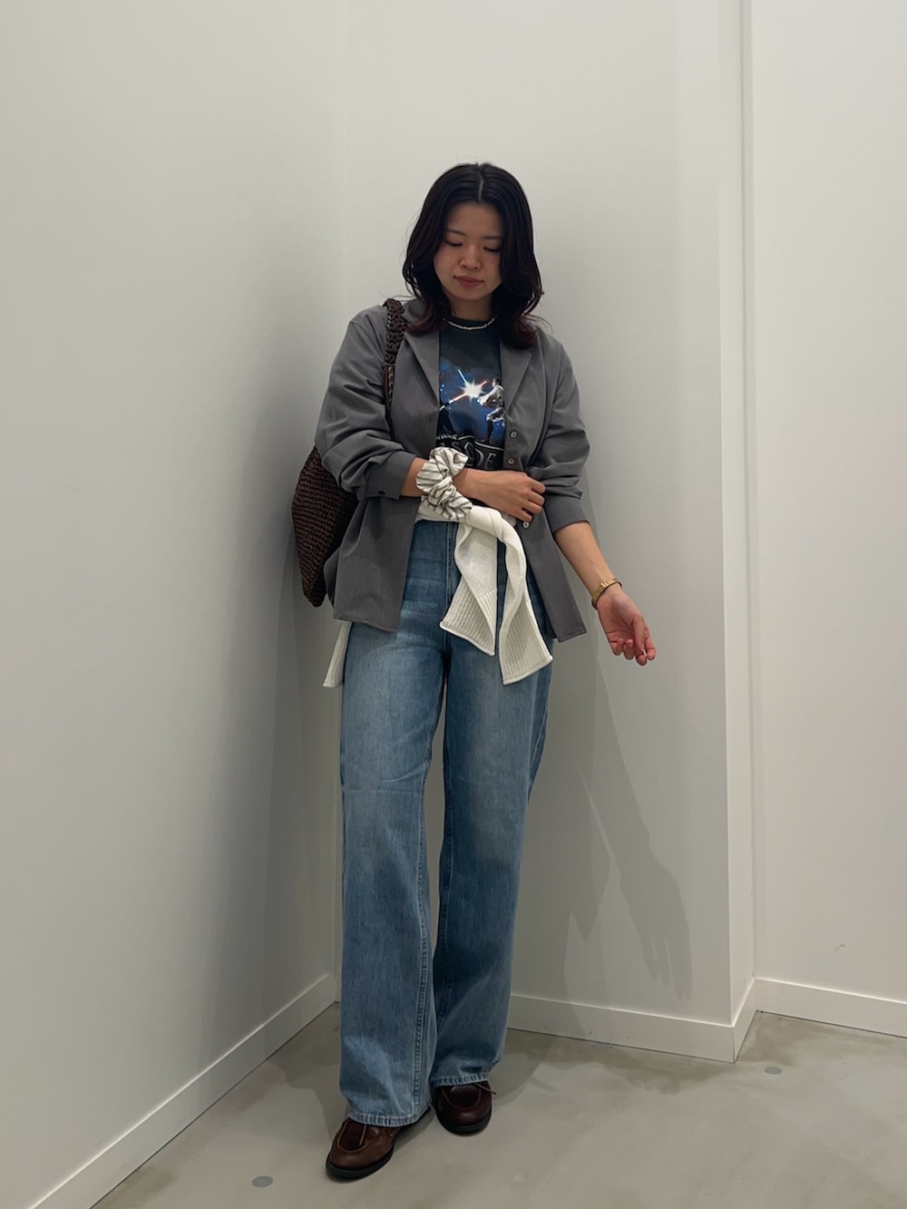 ブルー系のデニムパンツ、ホワイト系のニット/セーター、グレー系のTシャツ/カットソーを着用したレディースの春コーディネートの2枚目の写真