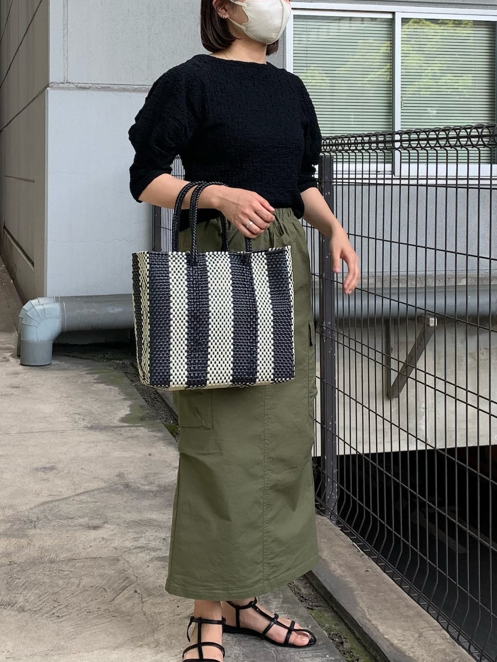 ブラック系のTシャツ/カットソー、グリーン系のスカートを着用したレディースの春コーディネートの2枚目の写真