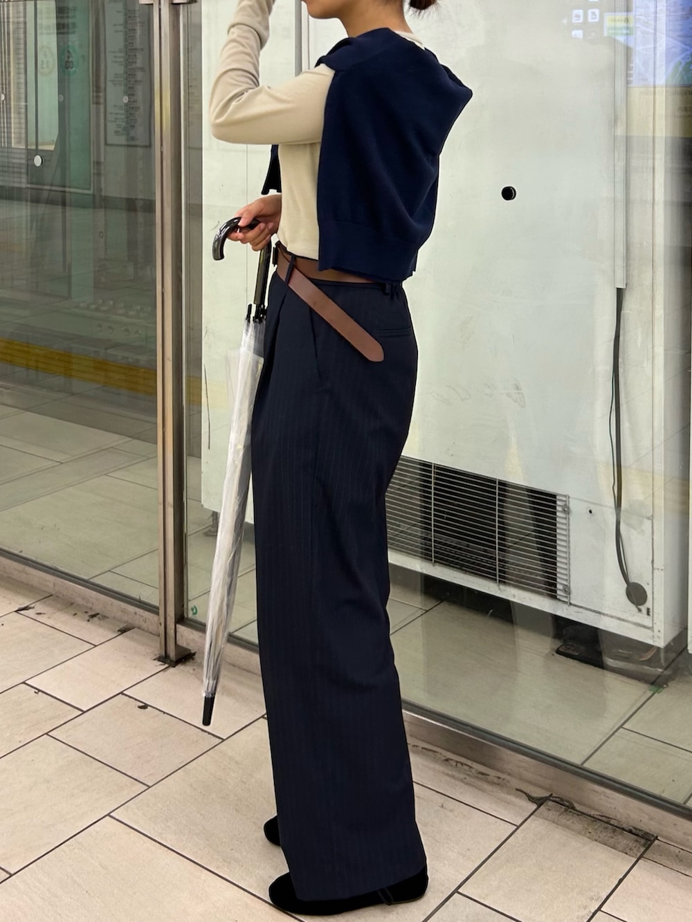 ブルー系のスラックス、ブラウン系のハンドバッグ、ベージュ系のTシャツ/カットソーを着用したレディースの秋コーディネートの2枚目の写真