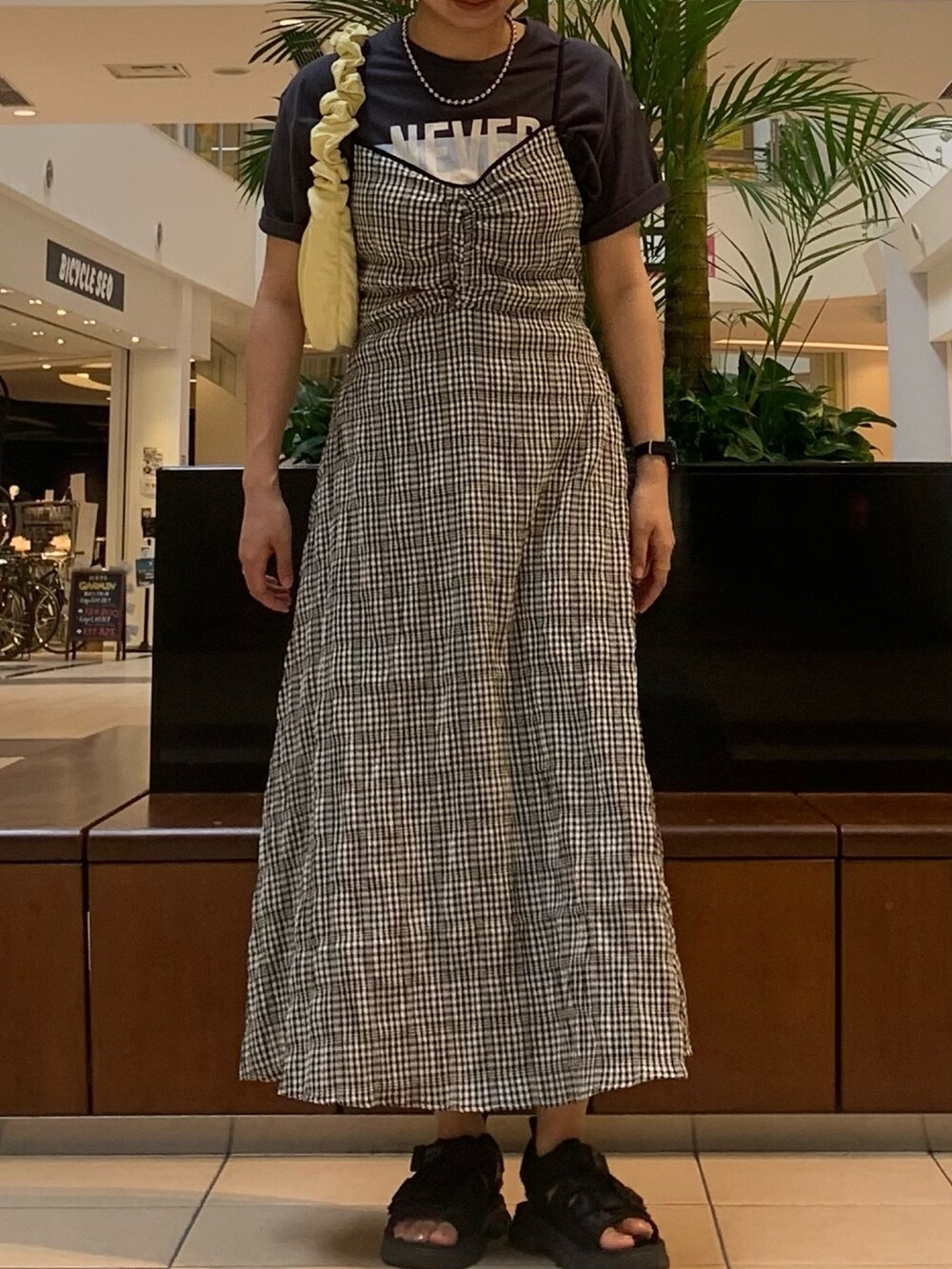 ブラック系のワンピース、グレー系のTシャツ/カットソー、イエロー系のショルダーバッグを着用したレディースの夏コーディネートの5枚目の写真