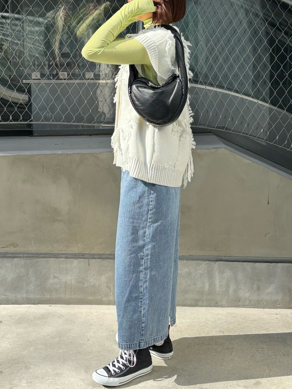 ブルー系のデニムスカート、ホワイト系のベスト、イエロー系のTシャツ/カットソーを着用したレディースの春コーディネートの2枚目の写真