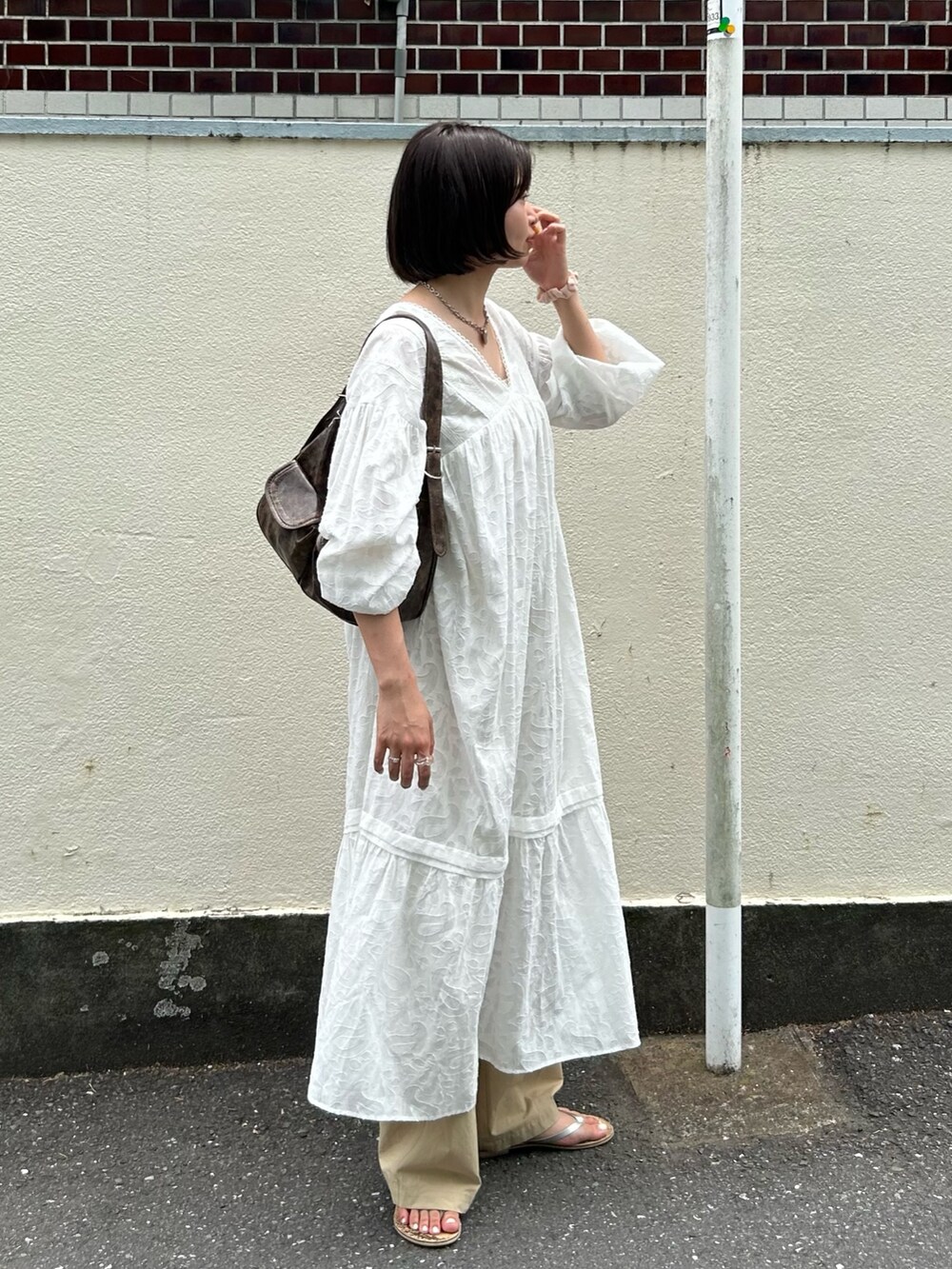 ホワイト系のワンピース、ベージュ系のチノパンツを着用したレディースの夏コーディネートの2枚目の写真