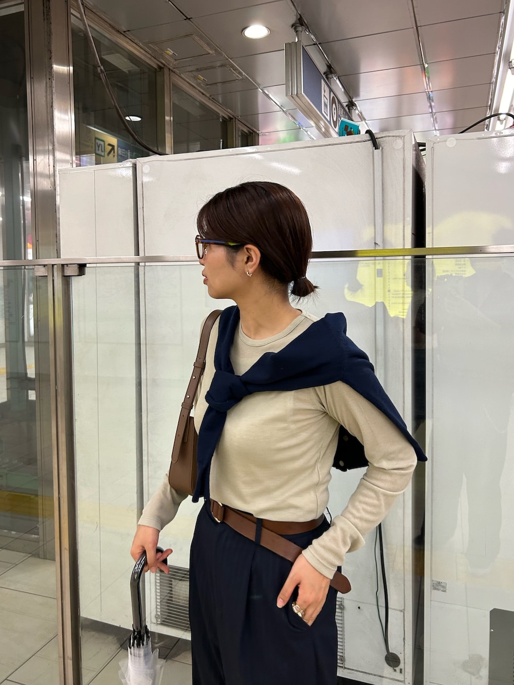 ブルー系のスラックス、ブラウン系のハンドバッグ、ベージュ系のTシャツ/カットソーを着用したレディースの秋コーディネートの4枚目の写真