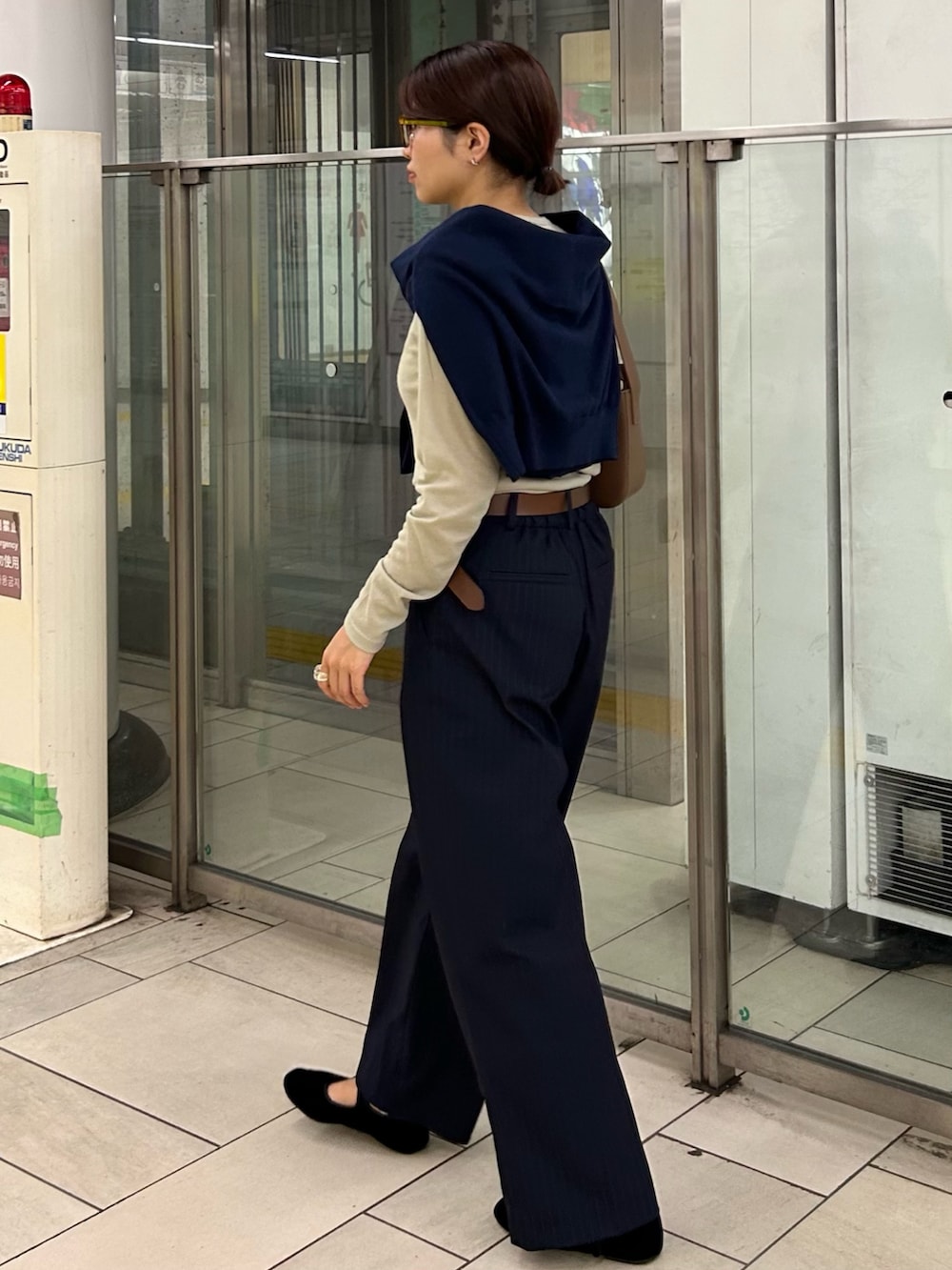 ブルー系のスラックス、ブラウン系のハンドバッグ、ベージュ系のTシャツ/カットソーを着用したレディースの秋コーディネートの3枚目の写真