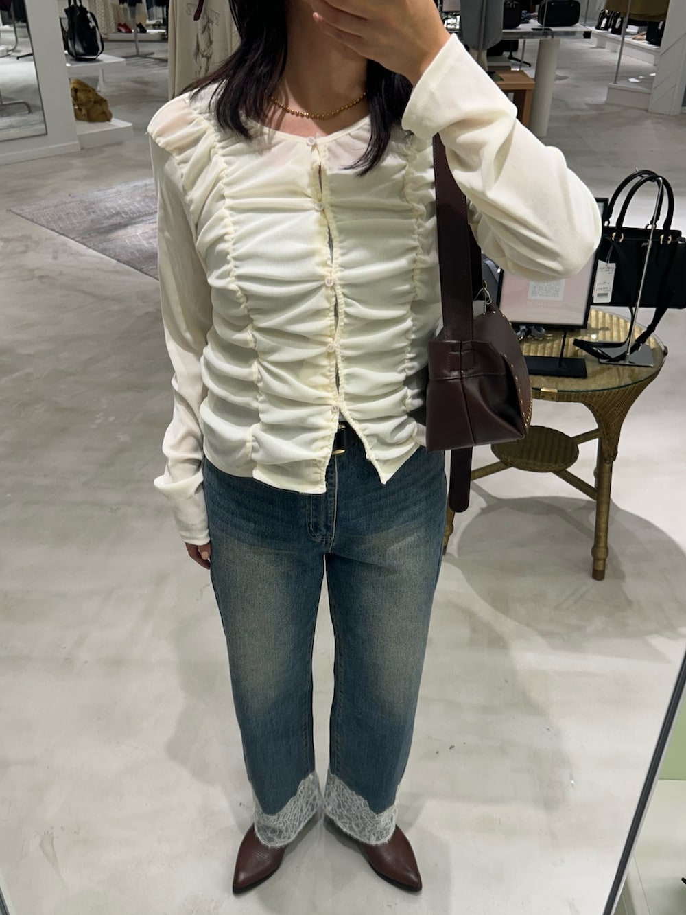 ホワイト系のカーディガン/ボレロ、ブルー系のデニムパンツ、ブラウン系のショルダーバッグを着用したレディースの秋コーディネートの4枚目の写真