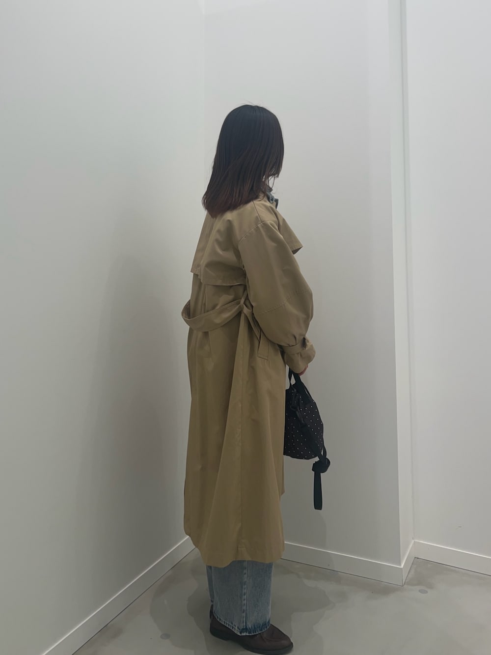 ベージュ系のトレンチコート、ブラック系のショルダーバッグ、ブルー系のデニムパンツを着用したレディースの冬コーディネートの5枚目の写真