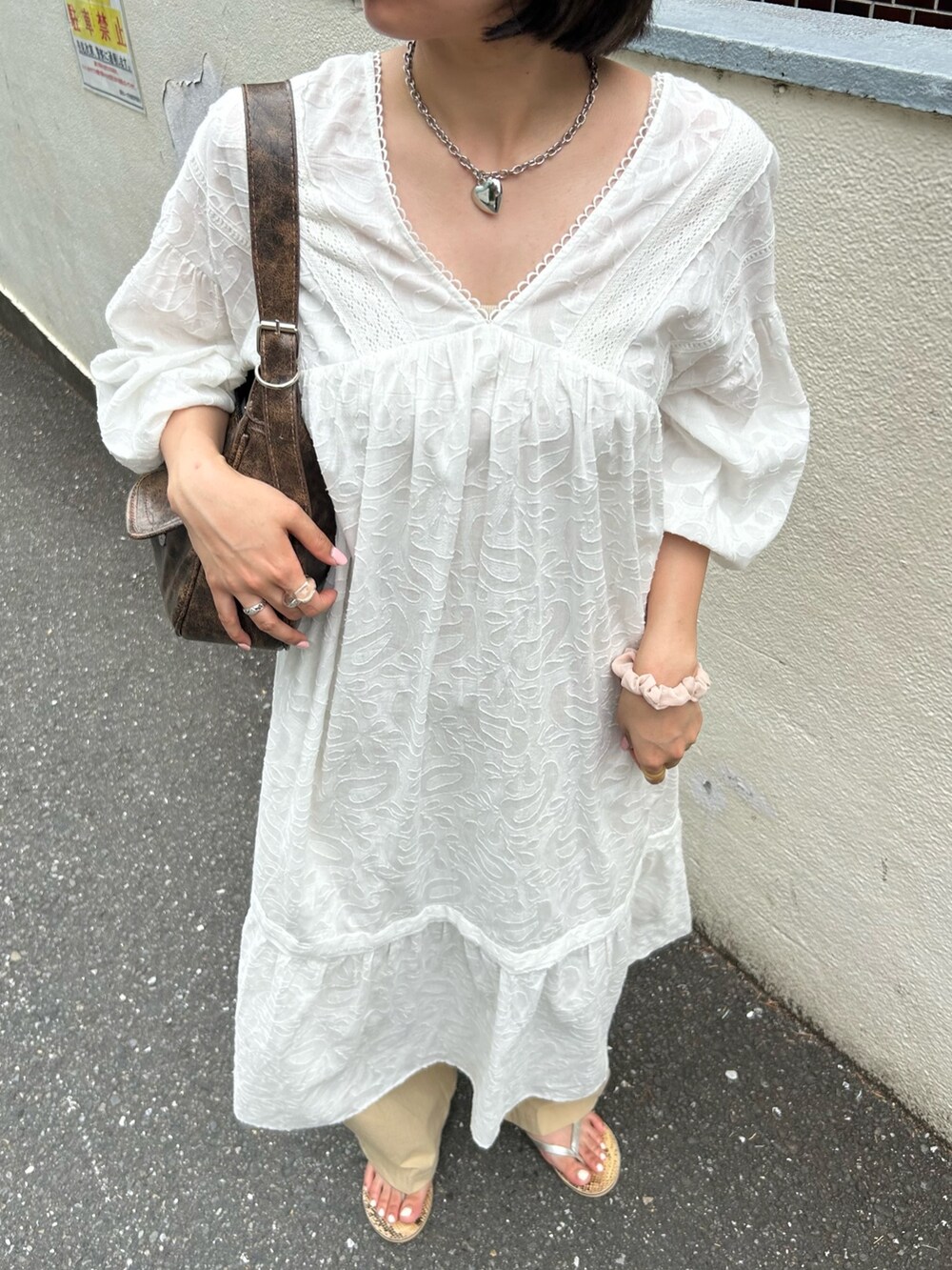 ホワイト系のワンピース、ベージュ系のチノパンツを着用したレディースの夏コーディネートの3枚目の写真