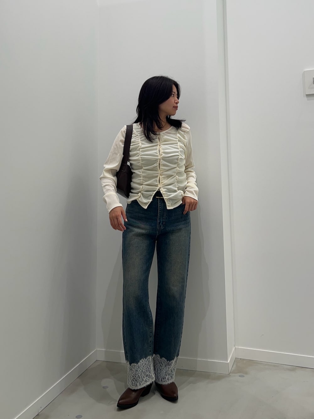ホワイト系のカーディガン/ボレロ、ブルー系のデニムパンツ、ブラウン系のショルダーバッグを着用したレディースの秋コーディネートの2枚目の写真