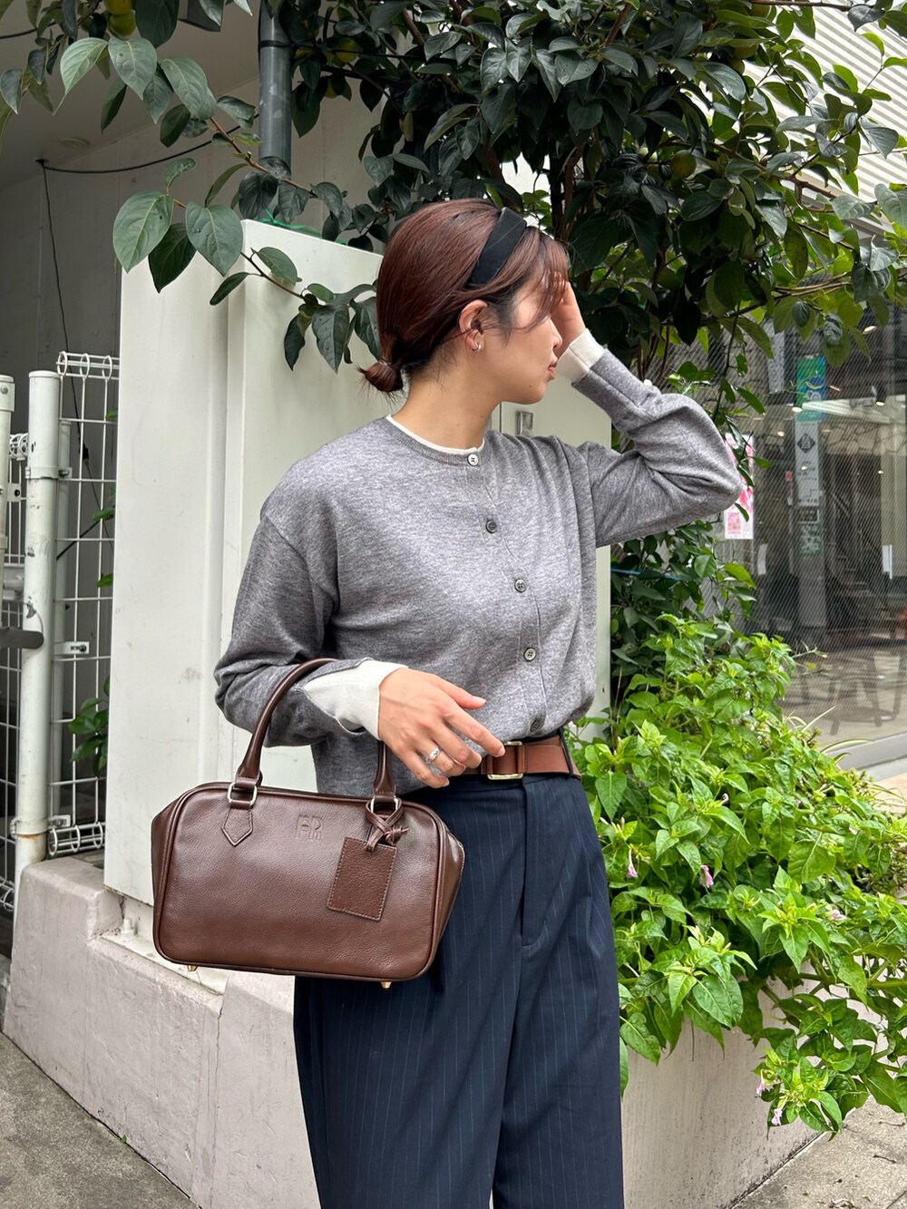 ブルー系のスラックス、ブラウン系のハンドバッグ、グレー系のカーディガン/ボレロを着用したレディースの秋コーディネートの3枚目の写真