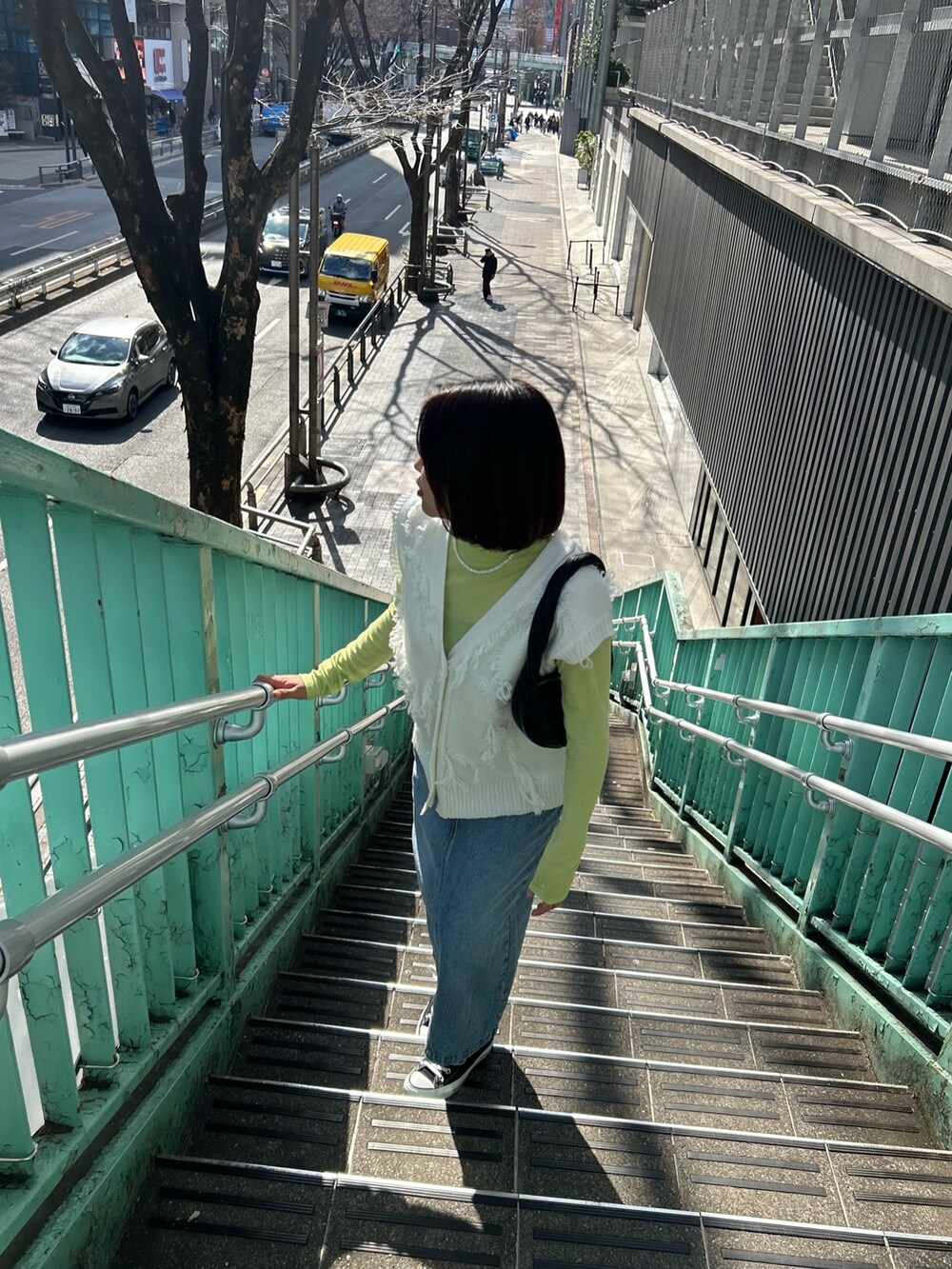 ブルー系のデニムスカート、ホワイト系のベスト、イエロー系のTシャツ/カットソーを着用したレディースの春コーディネートの3枚目の写真