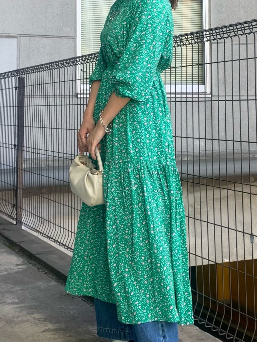 グリーン系のワンピース、ブルー系のデニムパンツ、ホワイト系のトートバッグを着用したレディースの春コーディネートの3枚目の写真