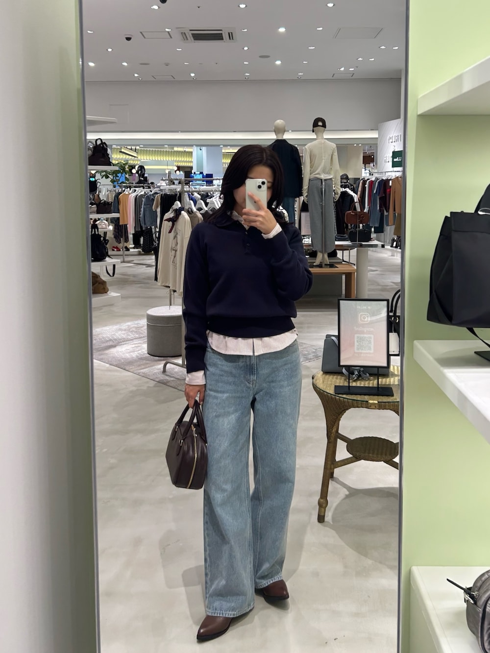 レッド系のシャツ/ブラウス、ブルー系のデニムパンツ、ブラウン系のボストンバッグを着用したレディースの秋コーディネートの4枚目の写真