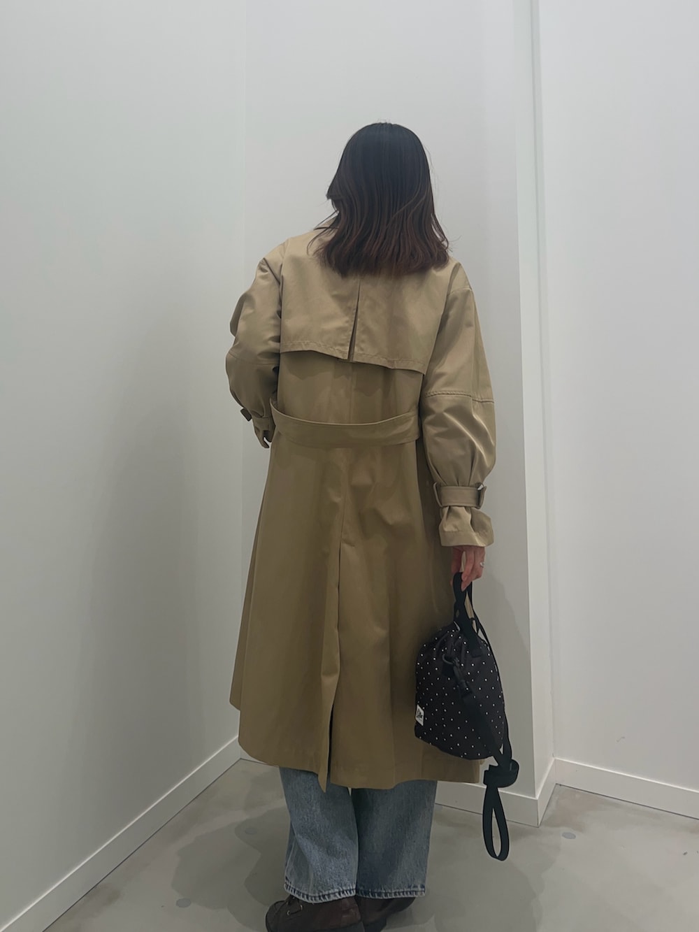 ベージュ系のトレンチコート、ブラック系のショルダーバッグ、ブルー系のデニムパンツを着用したレディースの冬コーディネートの4枚目の写真