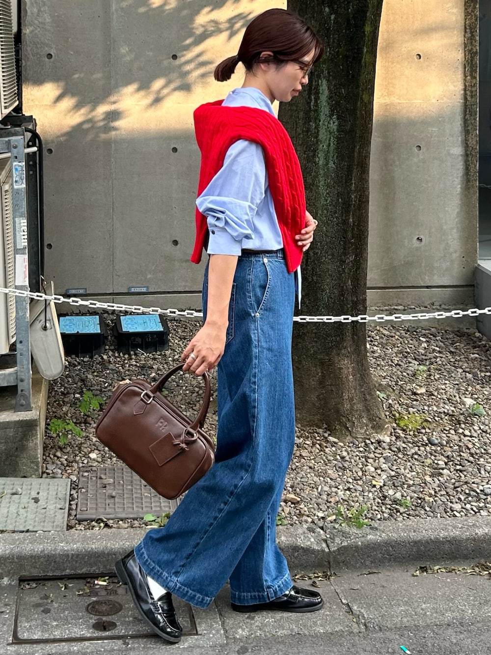 ブルー系のデニムパンツ、ブラウン系のハンドバッグ、レッド系のニット/セーターを着用したレディースの秋コーディネートの2枚目の写真