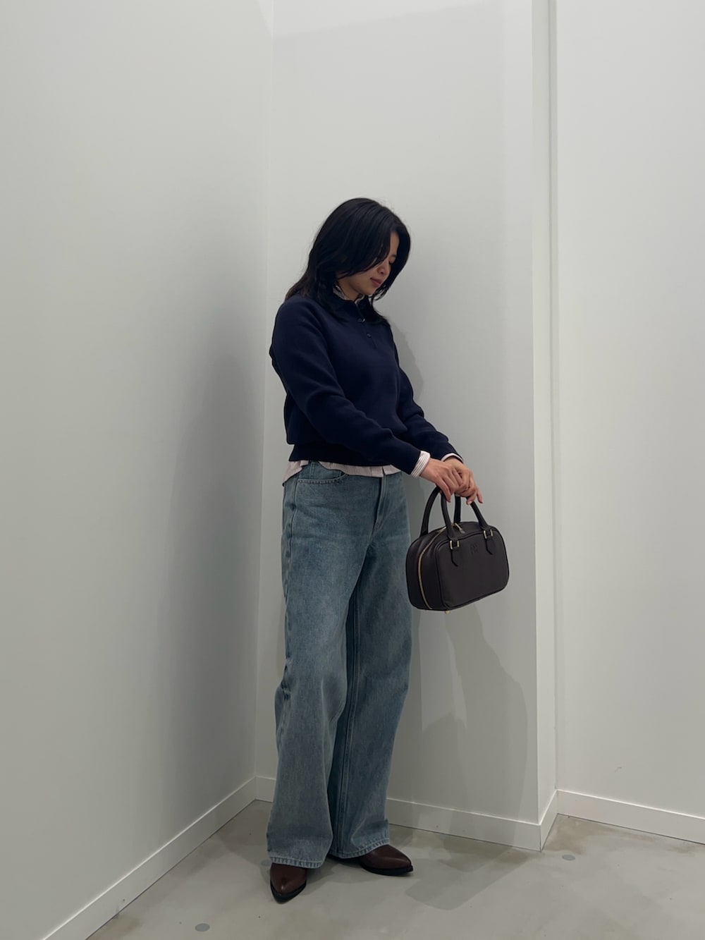 レッド系のシャツ/ブラウス、ブルー系のデニムパンツ、ブラウン系のボストンバッグを着用したレディースの秋コーディネートの2枚目の写真
