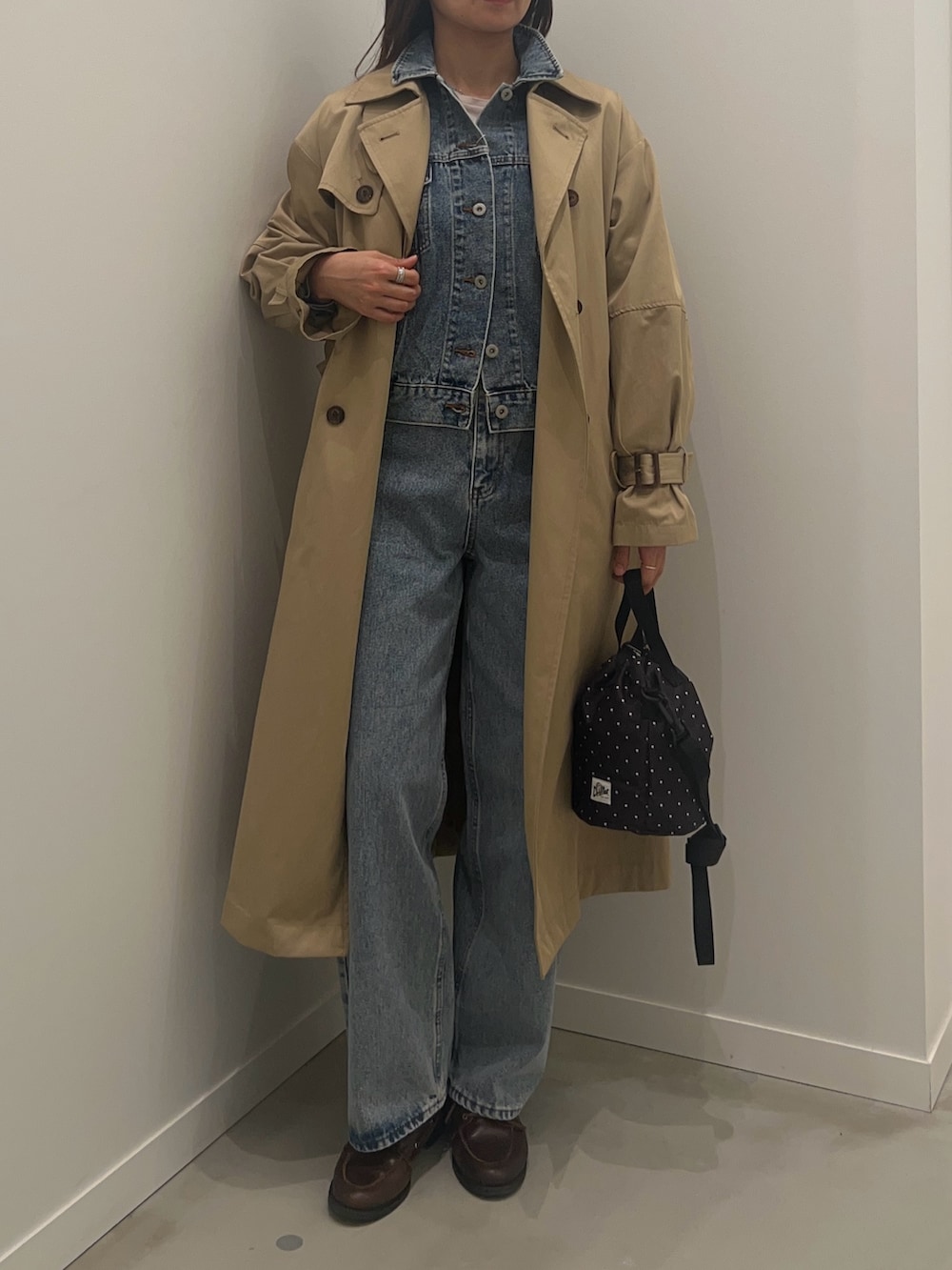 ベージュ系のトレンチコート、ブラック系のショルダーバッグ、ブルー系のデニムパンツを着用したレディースの冬コーディネートの3枚目の写真