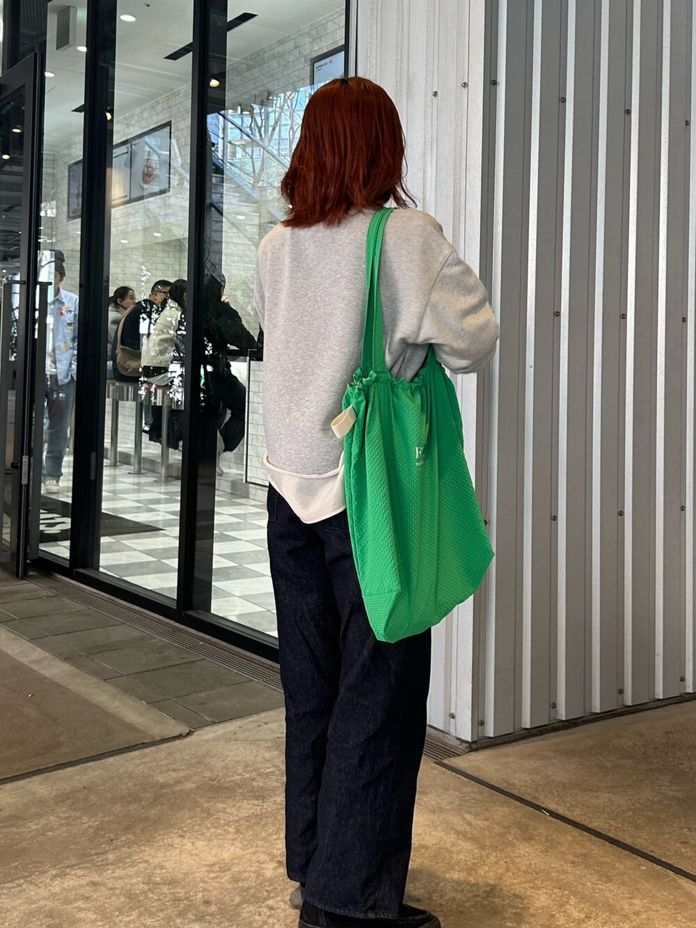 グレー系のスウェット、ホワイト系のシャツ/ブラウス、ブルー系のデニムパンツを着用したレディースの春コーディネートの5枚目の写真