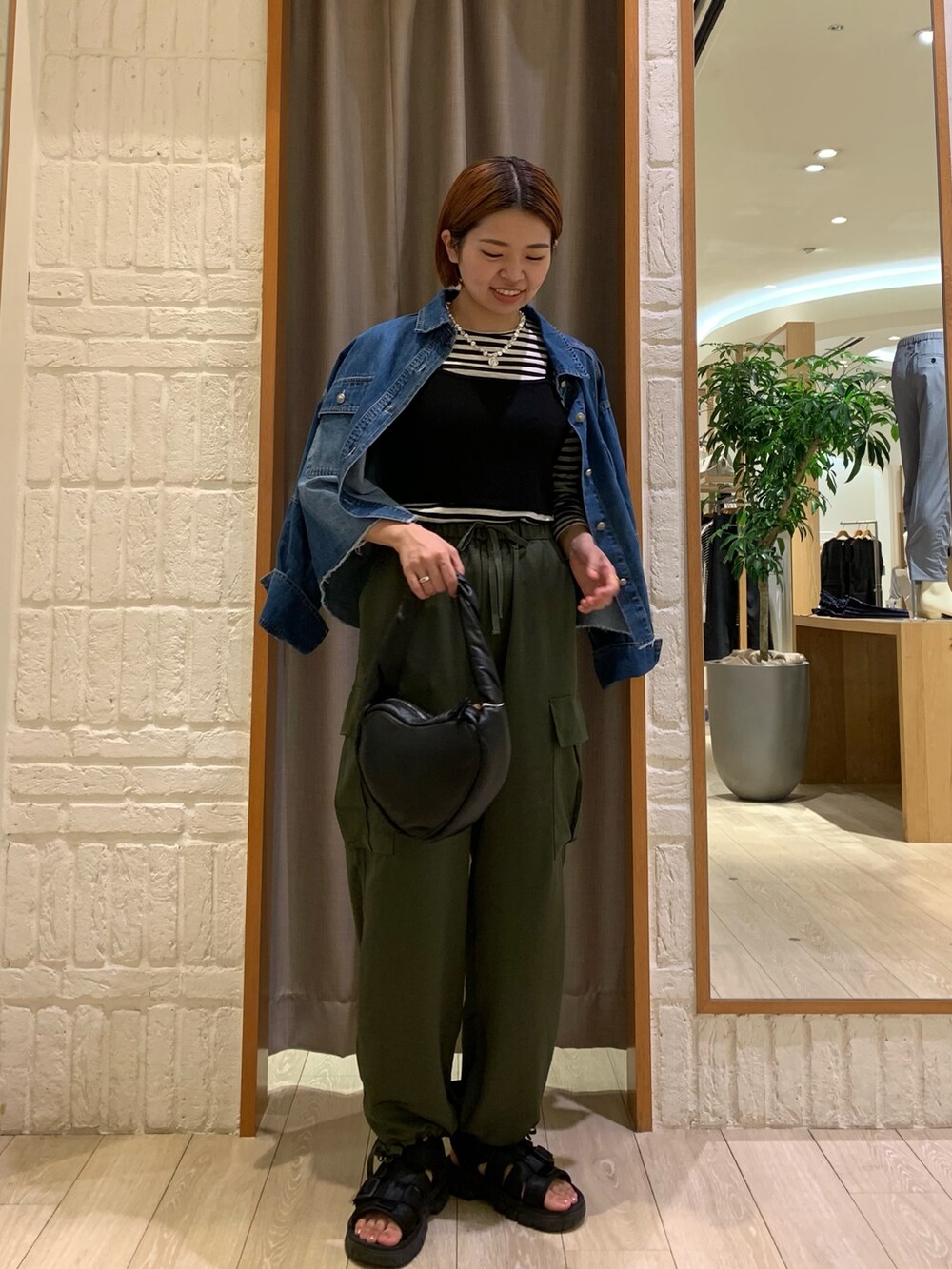 グリーン系のカーゴパンツ、ブルー系のシャツ/ブラウス、ブラック系のニット/セーターを着用したレディースの秋コーディネートの2枚目の写真