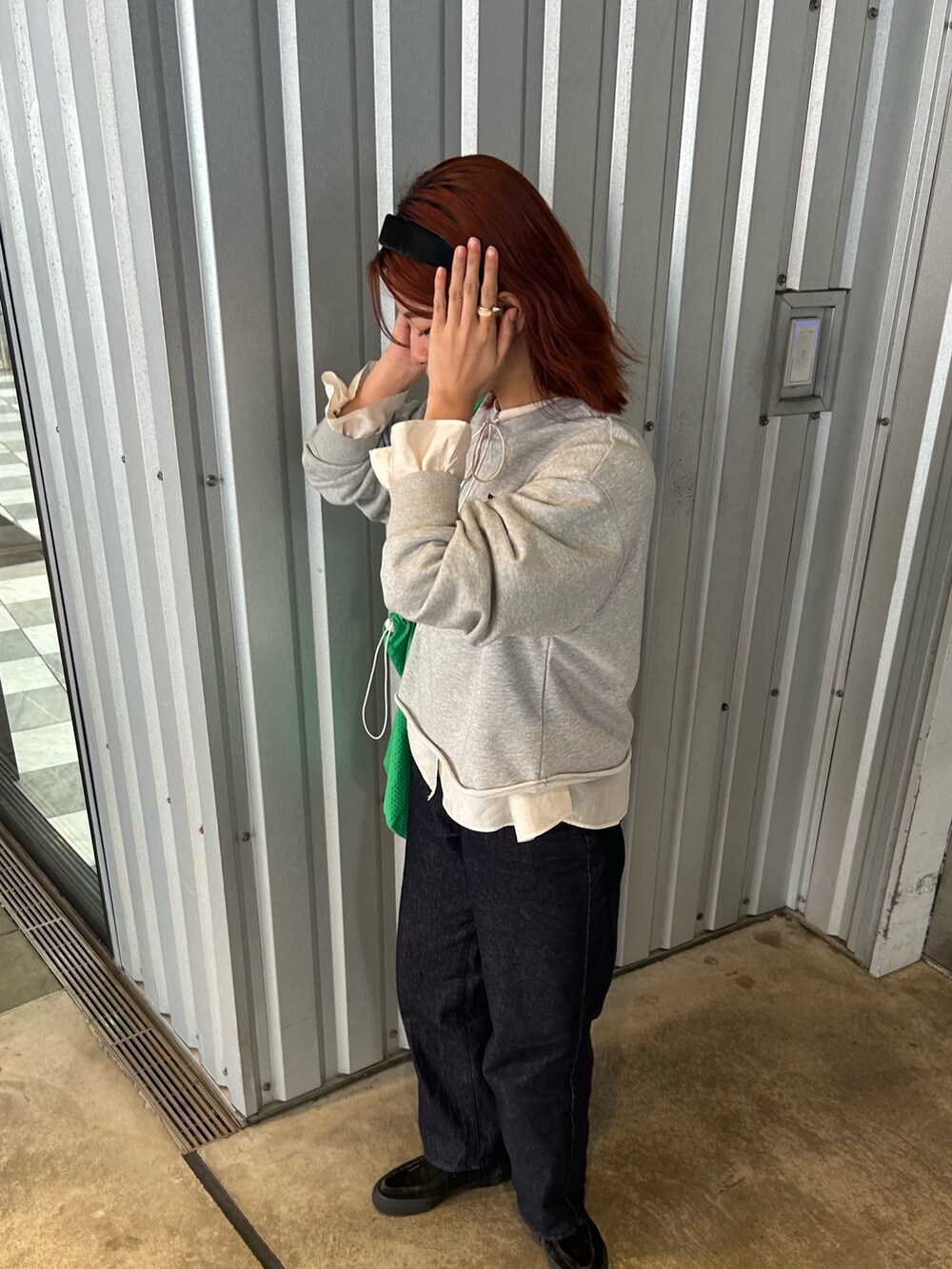 グレー系のスウェット、ホワイト系のシャツ/ブラウス、ブルー系のデニムパンツを着用したレディースの春コーディネートの6枚目の写真