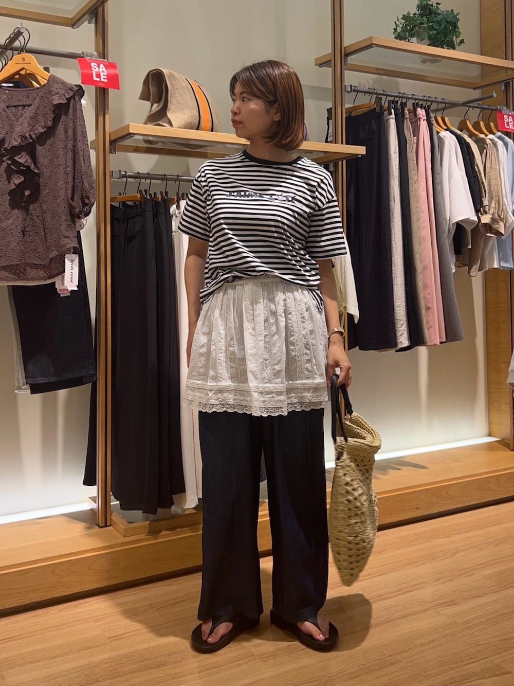 ブラック系のサンダル、ベージュ系のかごバッグ、ホワイト系のスカートを着用したレディースの夏コーディネートの4枚目の写真