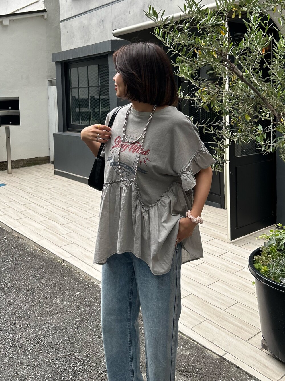 グレー系のTシャツ/カットソー、ブラック系のハンドバッグ、シルバー系のサンダルを着用したレディースの夏コーディネートの2枚目の写真