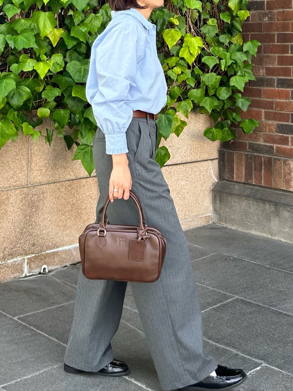 グレー系のスラックス、ブルー系のシャツ/ブラウス、ブラウン系のハンドバッグを着用したレディースの秋コーディネートの5枚目の写真