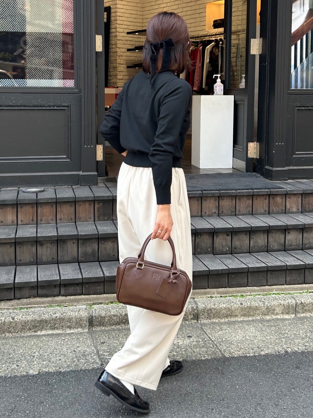 ホワイト系のその他パンツ、ブラウン系のハンドバッグ、ブラック系のニット/セーターを着用したレディースの秋コーディネートの6枚目の写真