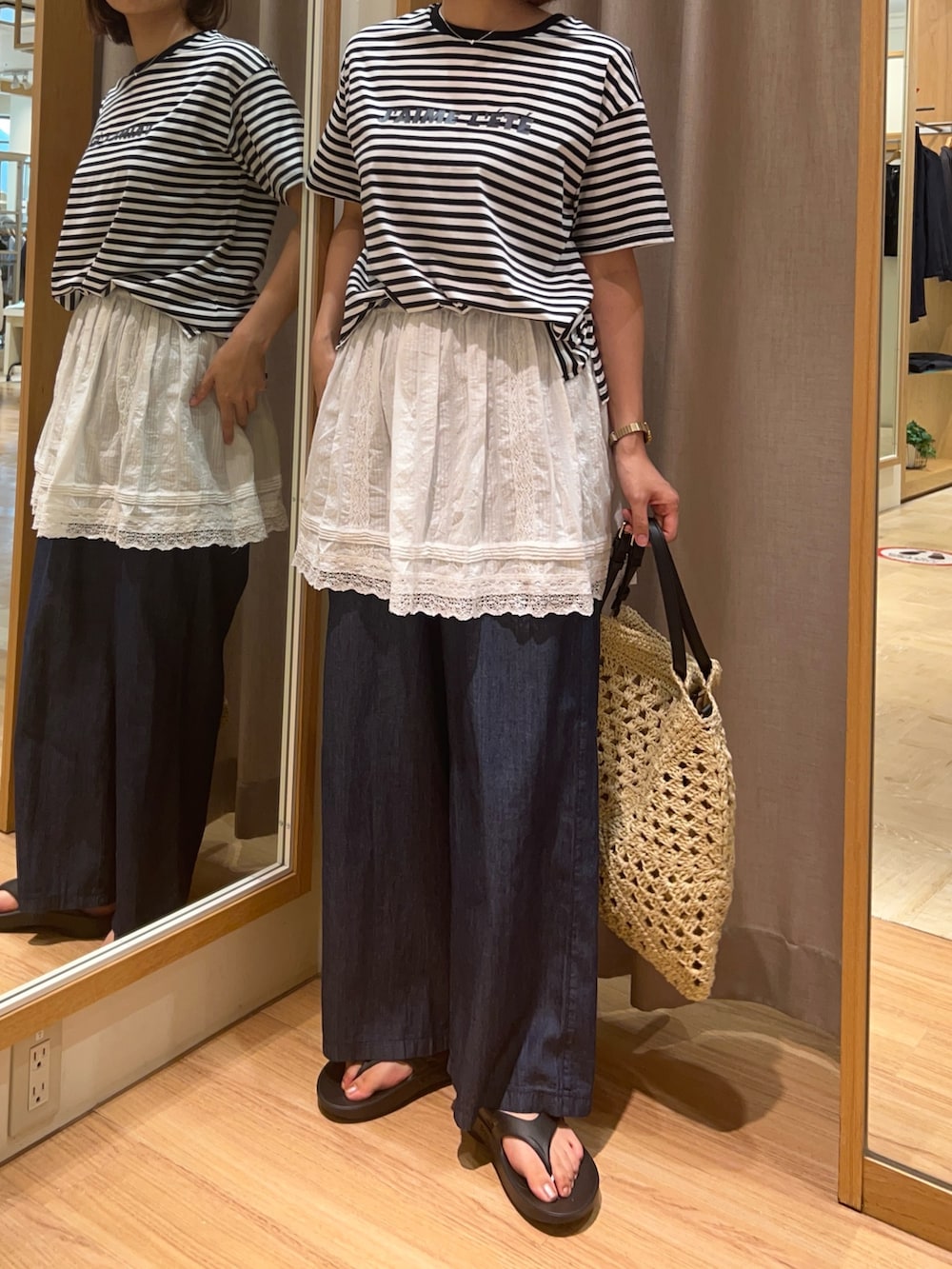 ブラック系のサンダル、ベージュ系のかごバッグ、ホワイト系のスカートを着用したレディースの夏コーディネートの2枚目の写真