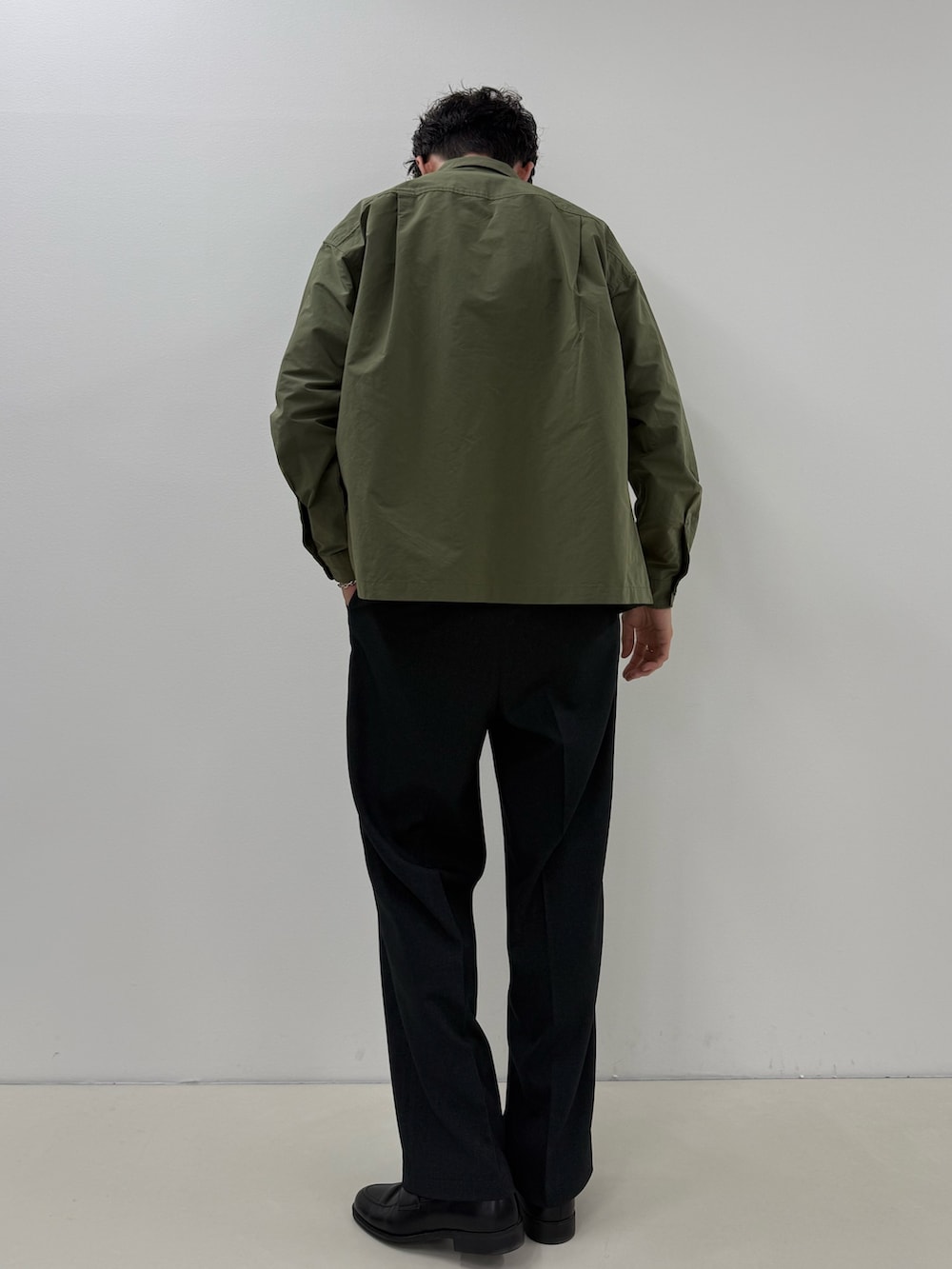 グリーン系のブルゾン、ホワイト系のTシャツ/カットソー、ブルー系のスラックスを着用したメンズの秋コーディネートの3枚目の写真