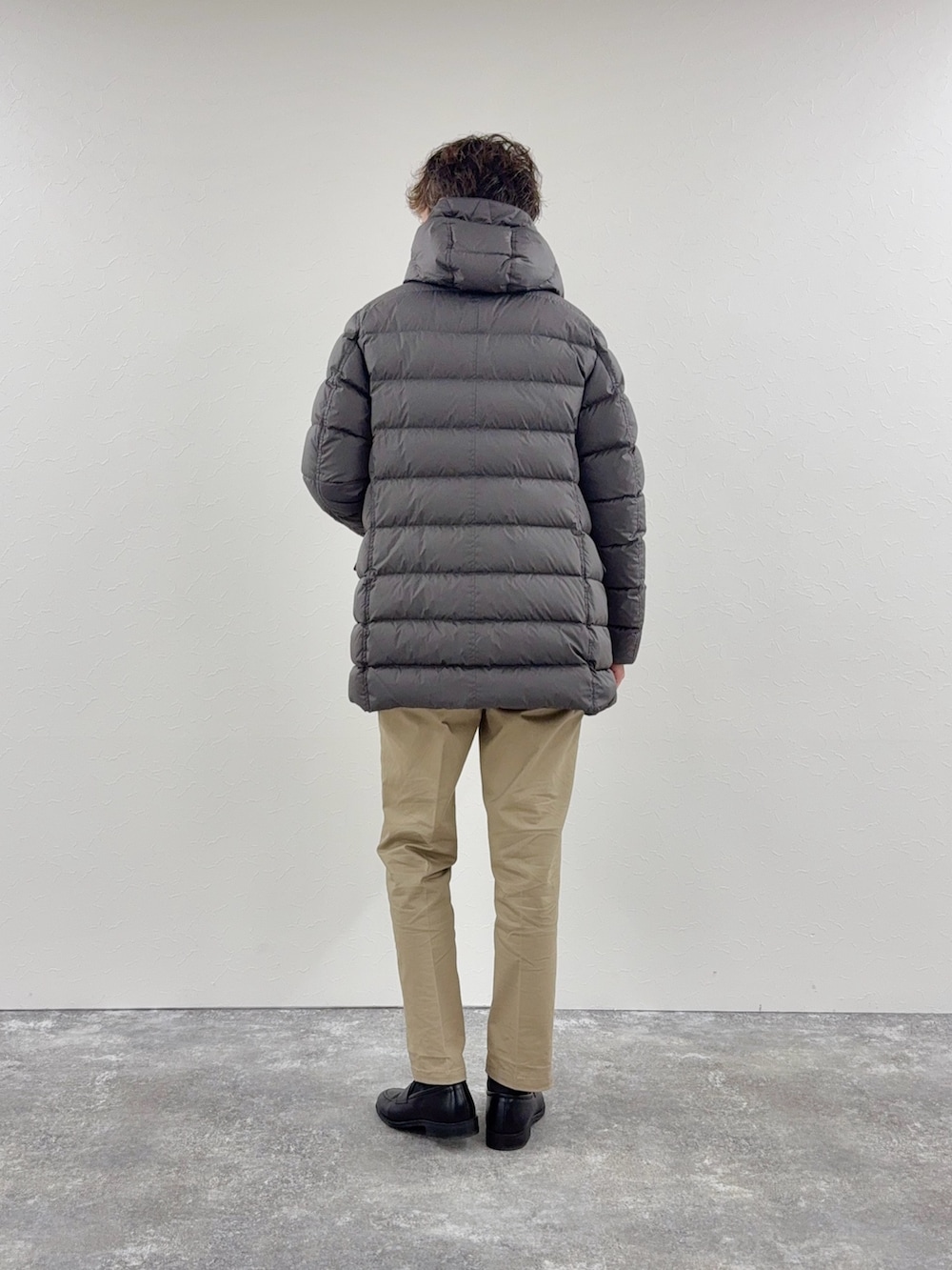 グレー系のダウンジャケット/コート、グレー系のニット/セーター、ブラック系のローファーを着用したメンズの秋コーディネートの3枚目の写真