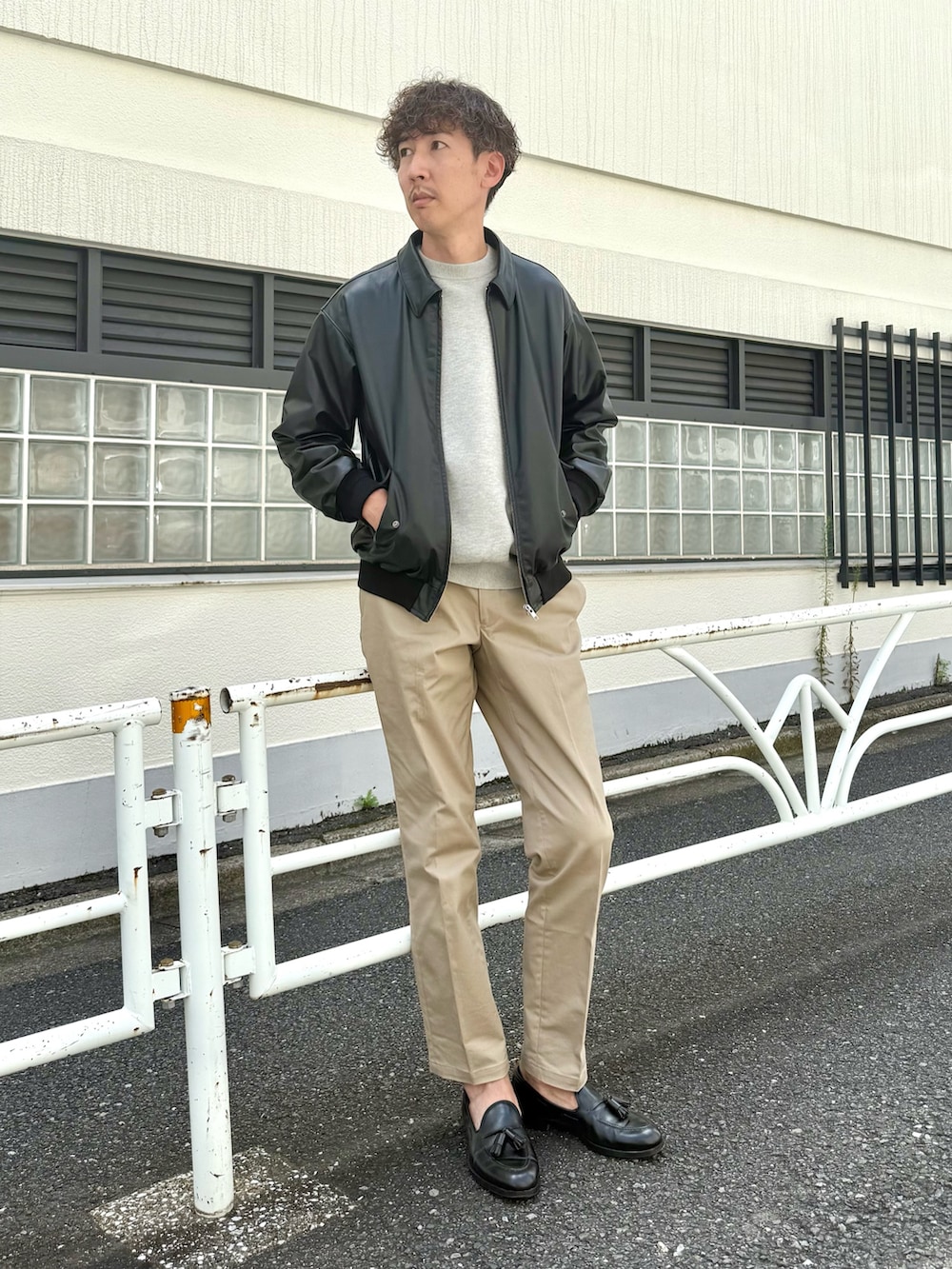 ブラック系のローファー、ブラック系のブルゾン、ベージュ系のチノパンツを着用したメンズの秋コーディネートの3枚目の写真