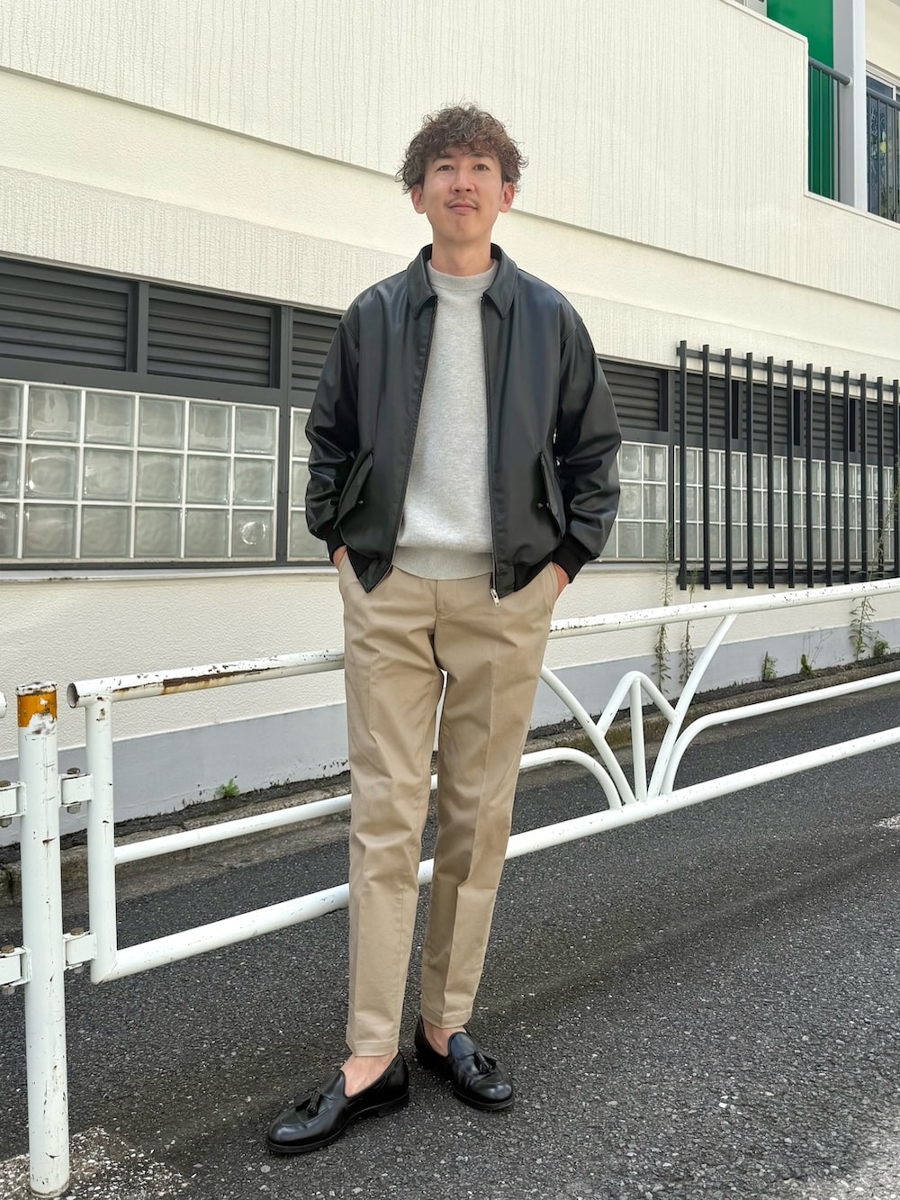 ブラック系のローファー、ブラック系のブルゾン、ベージュ系のチノパンツを着用したメンズの秋コーディネートの2枚目の写真
