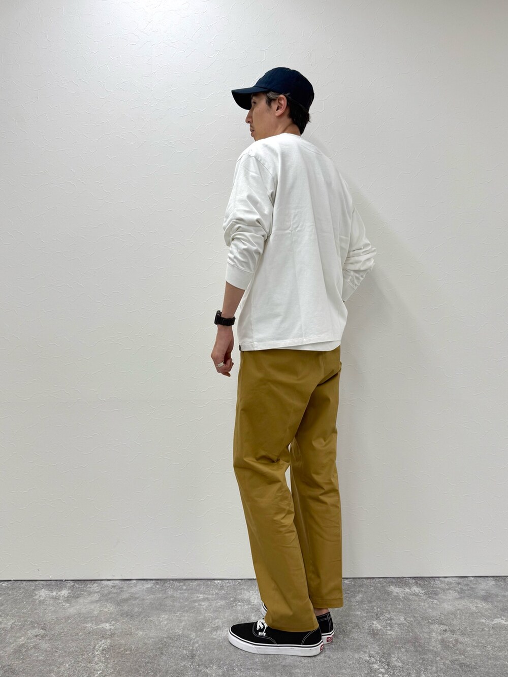 ホワイト系のTシャツ/カットソー、ベージュ系のチノパンツ、ブルー系のキャップを着用したメンズの秋コーディネートの2枚目の写真