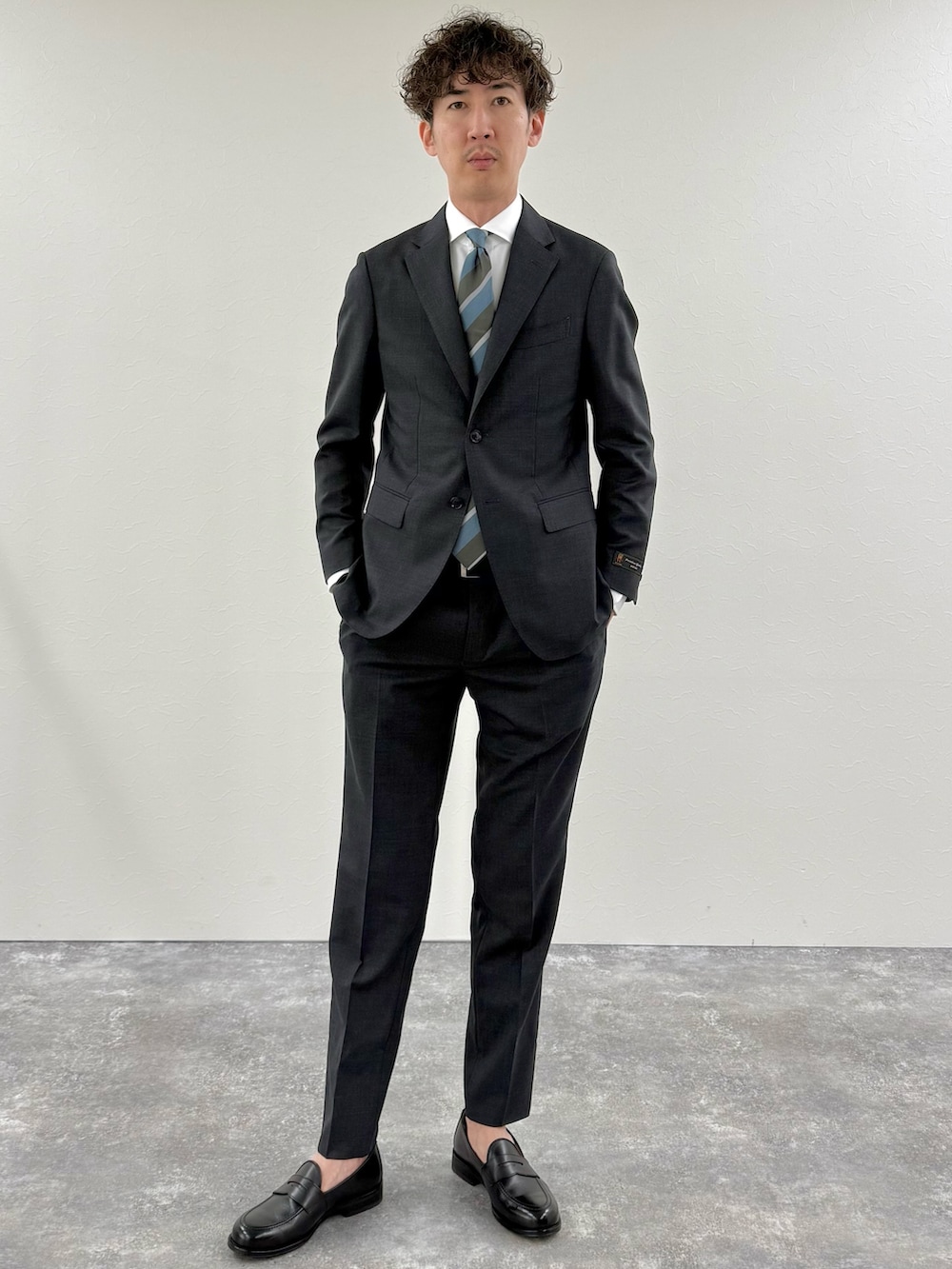 グレー系のセットアップ、ブルー系のネクタイ、ホワイト系のシャツ/ブラウスを着用したメンズの冬コーディネートの2枚目の写真