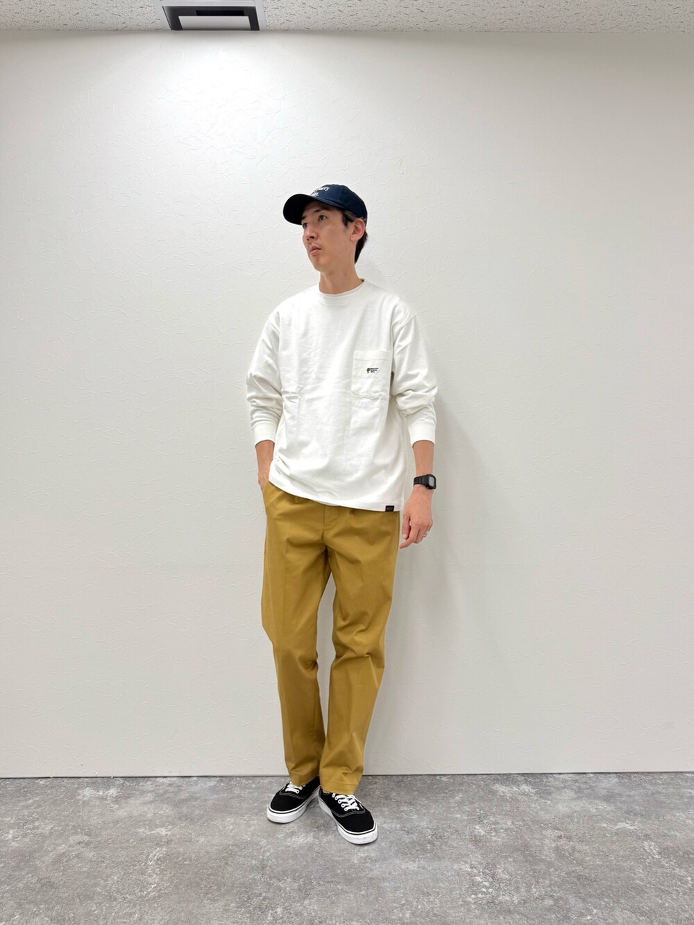 ホワイト系のTシャツ/カットソー、ベージュ系のチノパンツ、ブルー系のキャップを着用したメンズの秋コーディネートの3枚目の写真