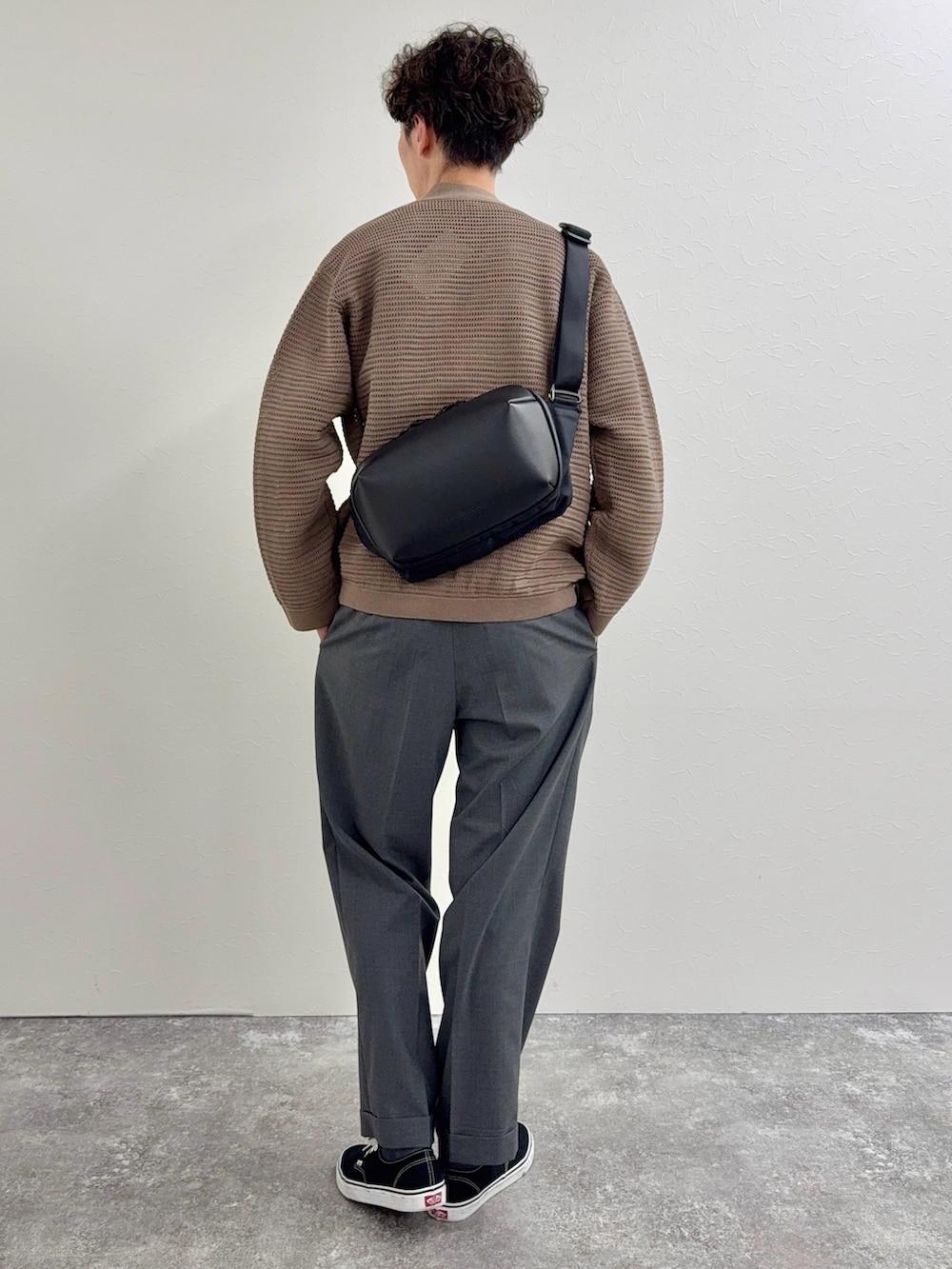 ブラック系のショルダーバッグ、ホワイト系のTシャツ/カットソー、グレー系のスラックスを着用したメンズの春コーディネートの2枚目の写真