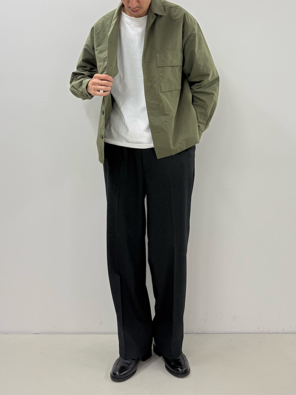 グリーン系のブルゾン、ホワイト系のTシャツ/カットソー、ブルー系のスラックスを着用したメンズの秋コーディネートの2枚目の写真