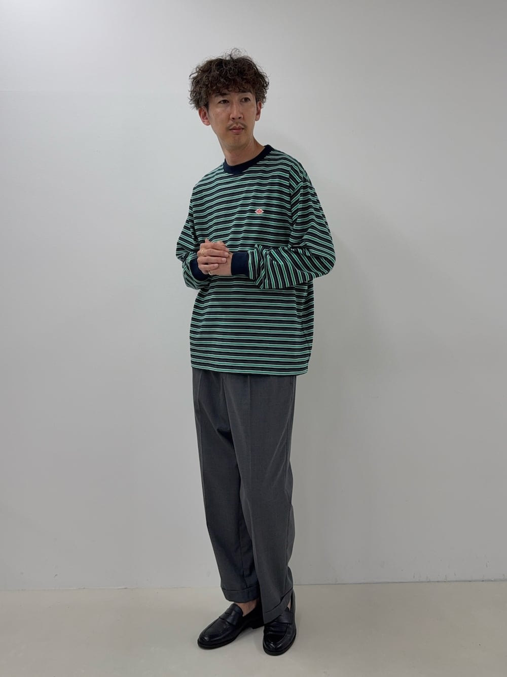 ブルー系のTシャツ/カットソー、グレー系のスラックス、ブラック系のローファーを着用したメンズの夏コーディネートの2枚目の写真