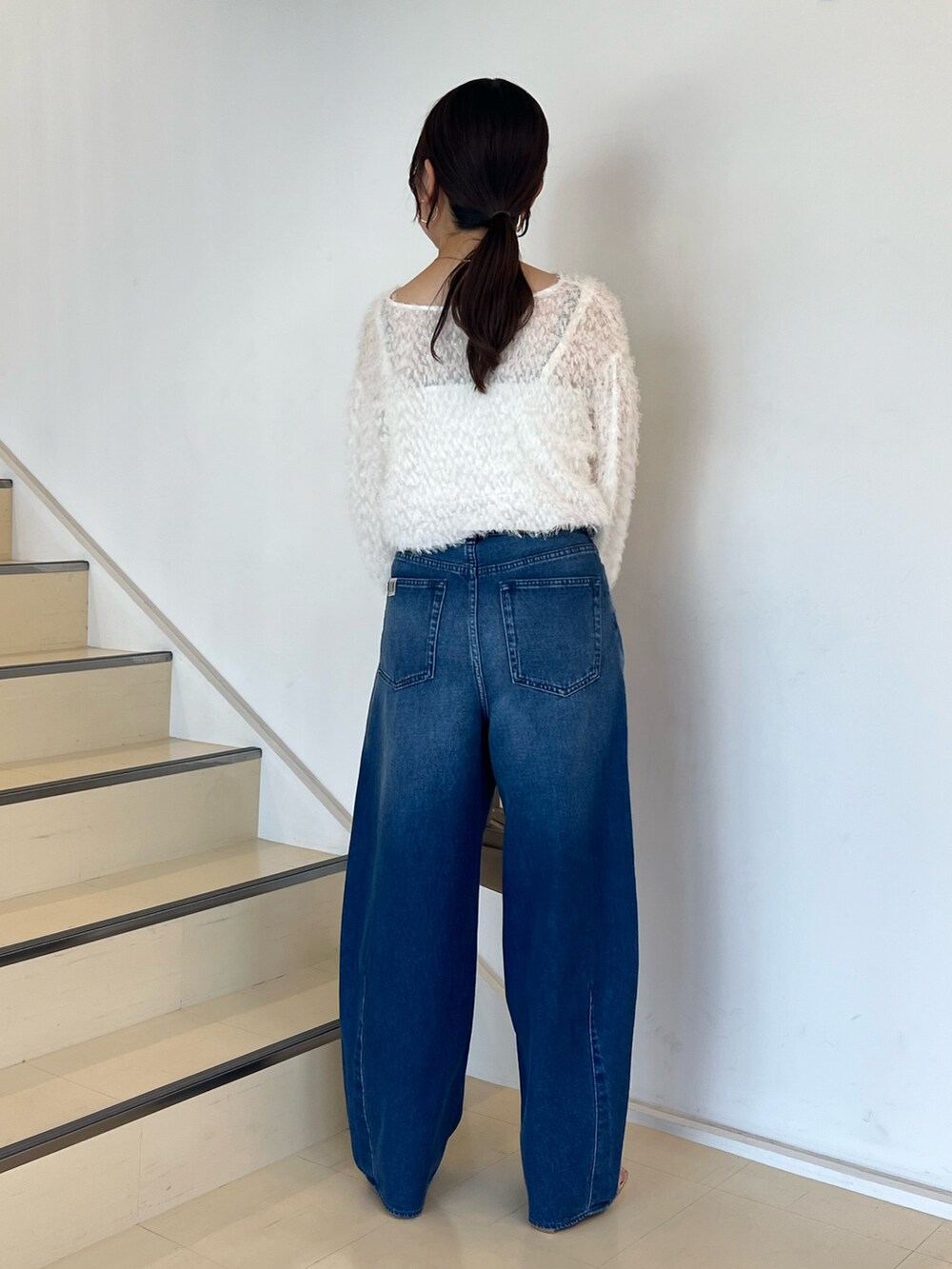 ブルー系のデニムパンツ、ホワイト系のシャツ/ブラウス、ホワイト系のボストンバッグを着用したレディースの夏コーディネートの5枚目の写真