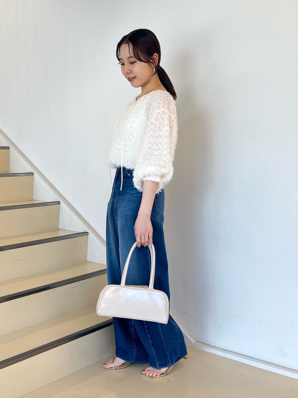 ブルー系のデニムパンツ、ホワイト系のシャツ/ブラウス、ホワイト系のボストンバッグを着用したレディースの夏コーディネートの2枚目の写真