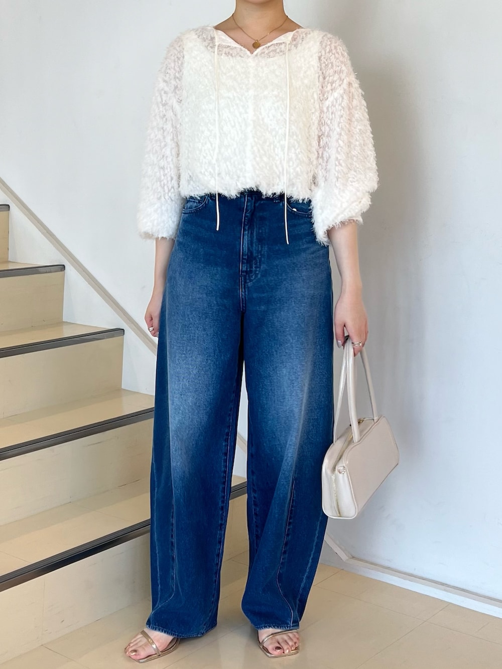 ブルー系のデニムパンツ、ホワイト系のシャツ/ブラウス、ホワイト系のボストンバッグを着用したレディースの夏コーディネートの3枚目の写真