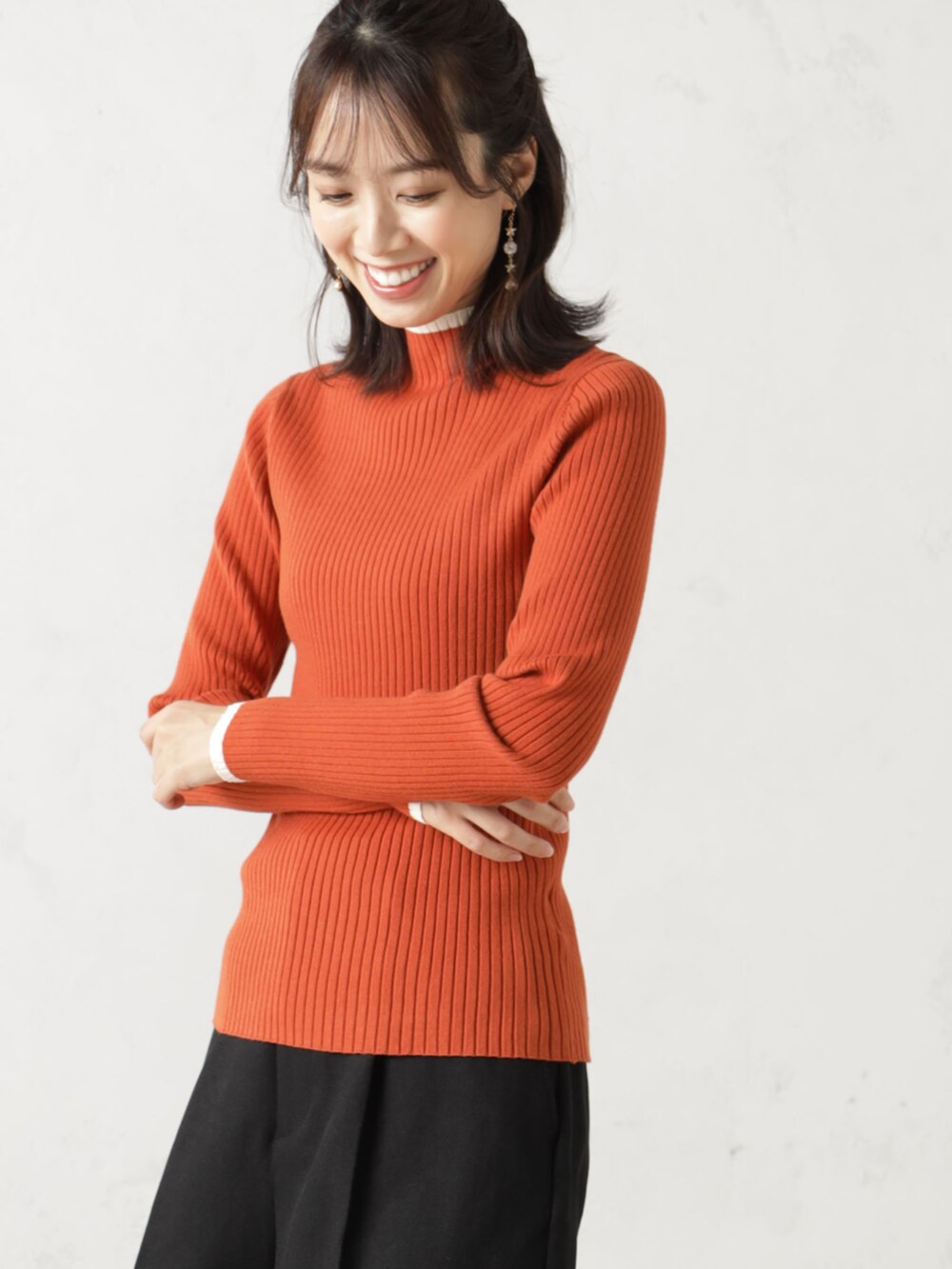 ブラック系のその他パンツ、オレンジ系のニット/セーターを着用したレディースの冬コーディネートの3枚目の写真
