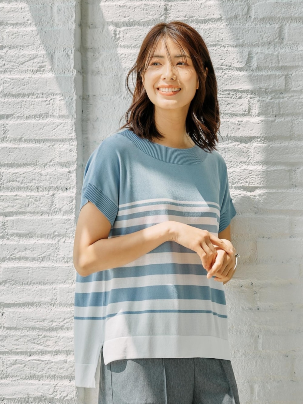 ブルー系のニット/セーターを着用したレディースの夏コーディネートの2枚目の写真