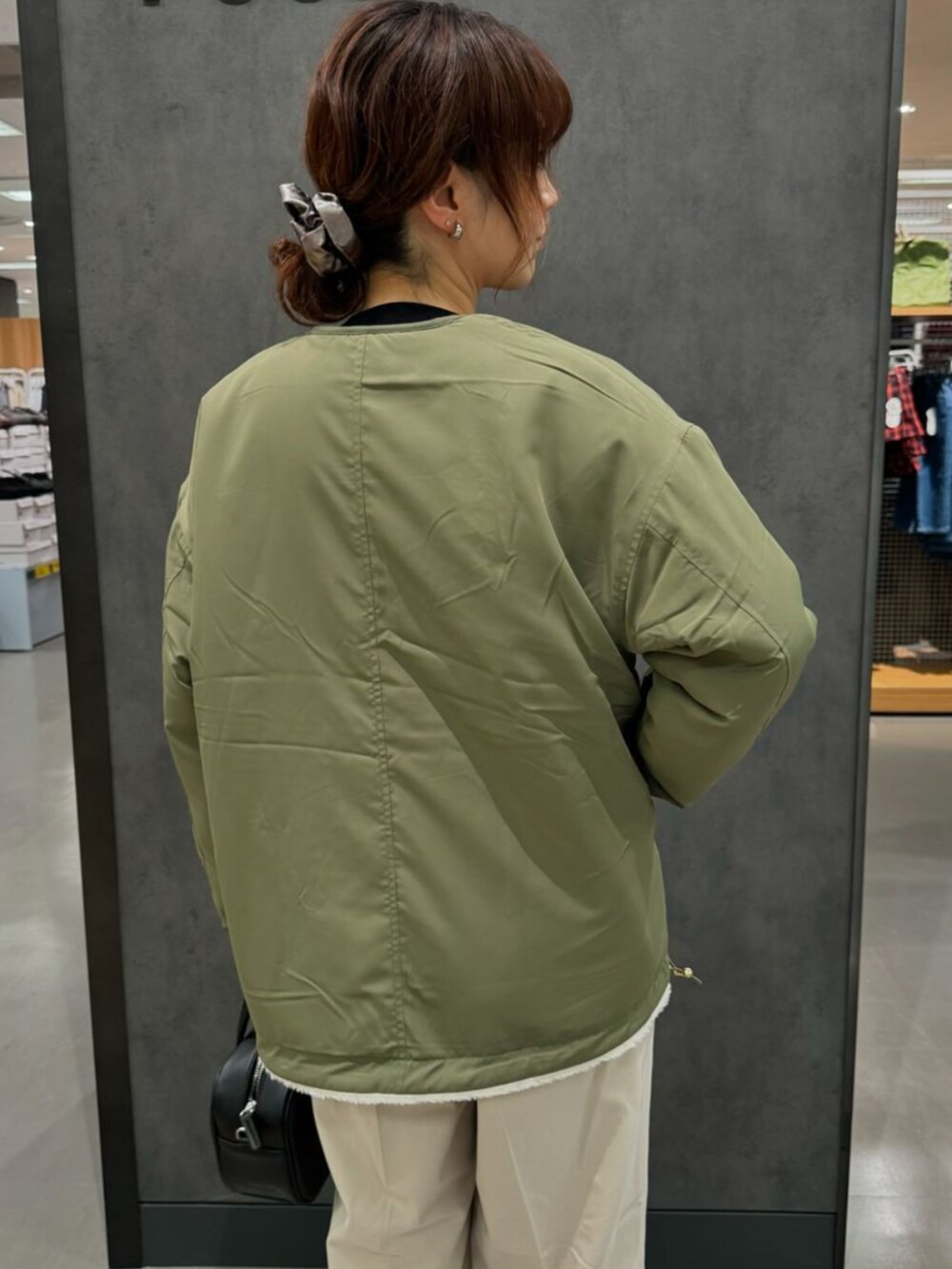 グリーン系のブルゾン、ベージュ系のチノパンツを着用したレディースの秋コーディネートの3枚目の写真