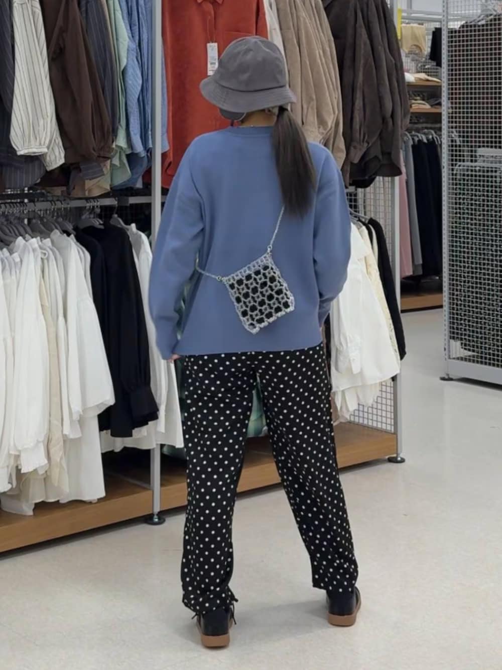 ブルー系のニット/セーター、ホワイト系のショルダーバッグ、ブラック系のスニーカーを着用したレディースの冬コーディネートの2枚目の写真