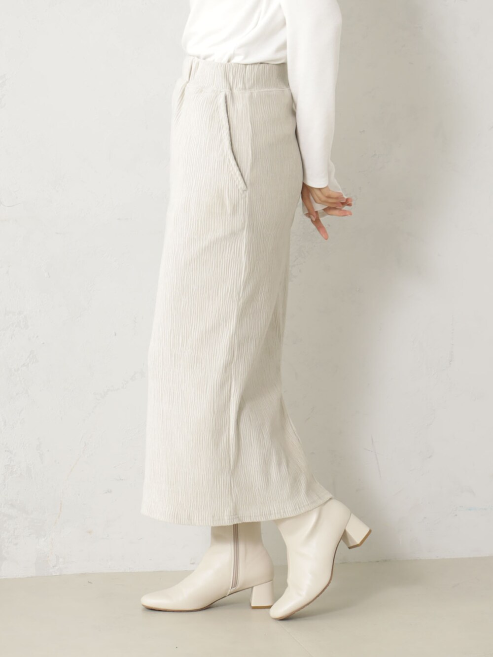 ベージュ系のブーツ、グレー系のニット/セーター、ベージュ系のスカートを着用したレディースの冬コーディネートの3枚目の写真