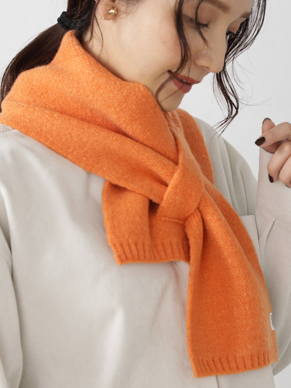 オレンジ系のマフラーを着用したレディースの秋コーディネートの2枚目の写真